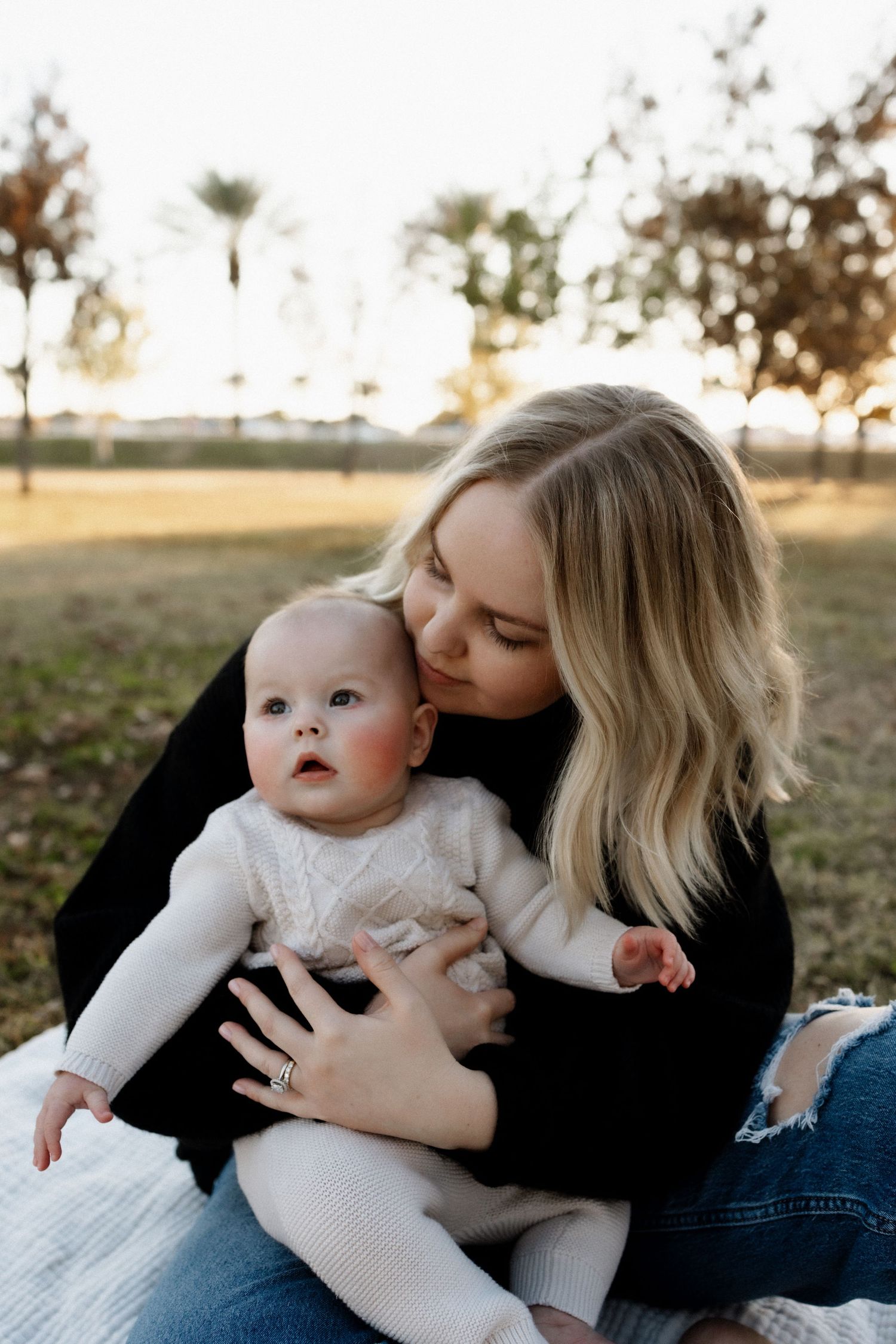 Sweet moment between parent and baby sitting on blanket during sunset.