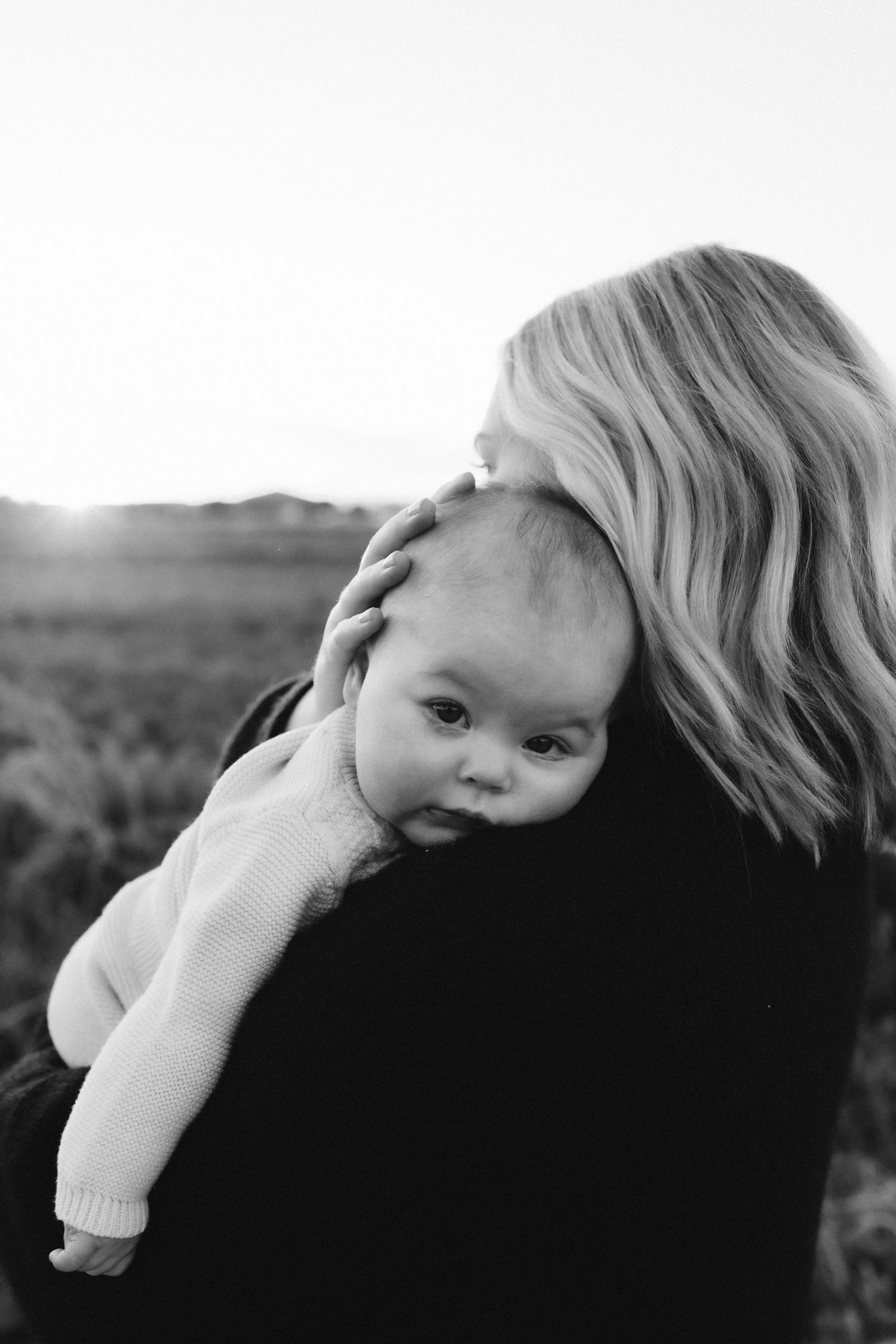 A sweet monochrome image of a parent holding their baby over their shoulder.