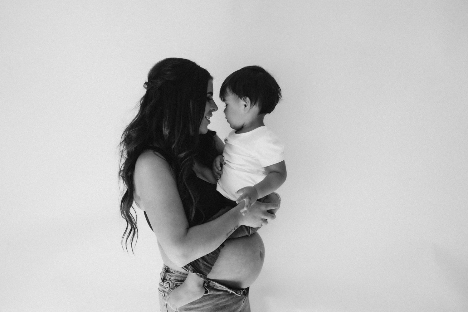 A tender black and white moment between parent and baby against a stark white background.