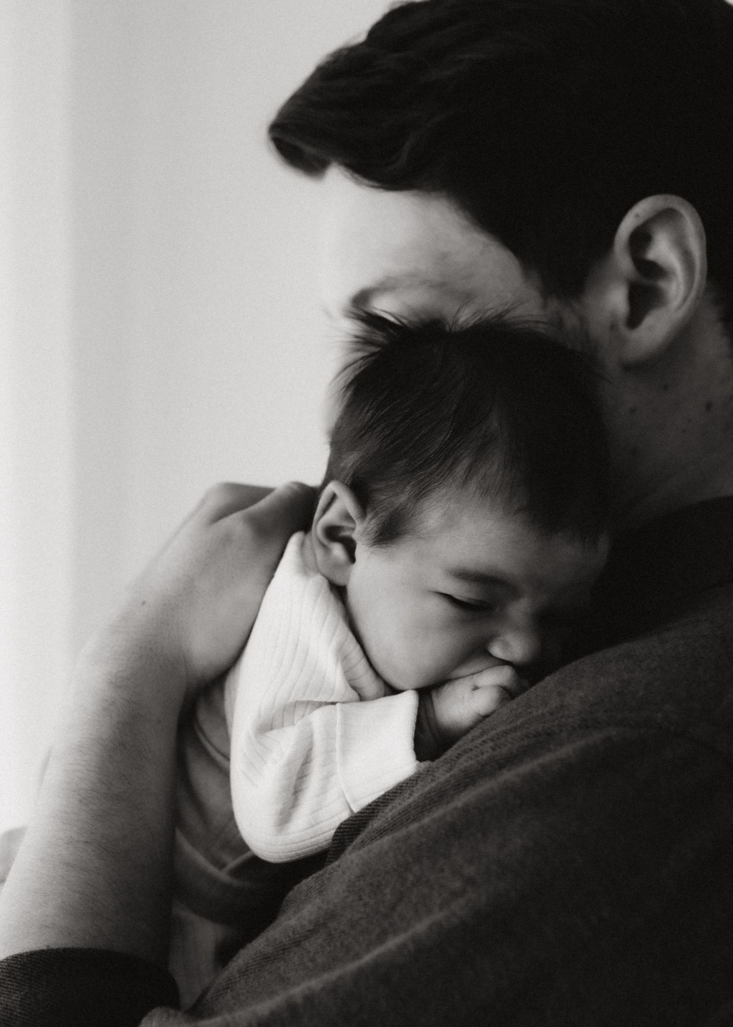 Intimate black and white photo of parent and baby sharing tender moment.