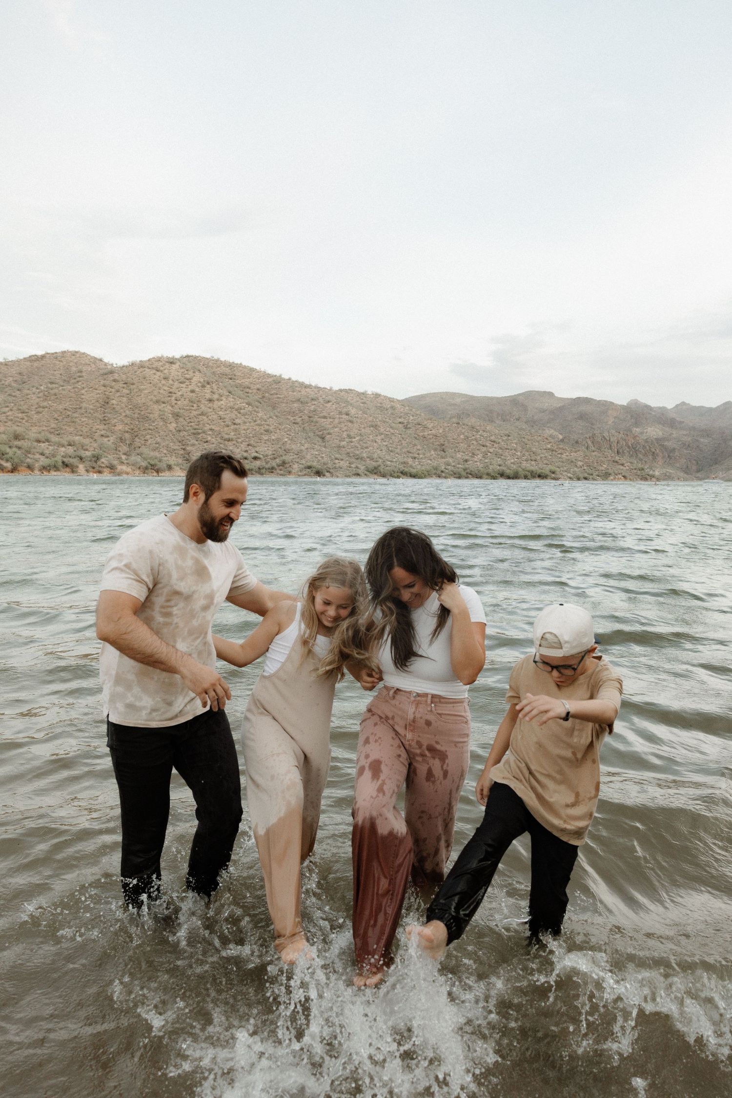 Group playing in the water at a lake surrounded by mountains during a photo session.
