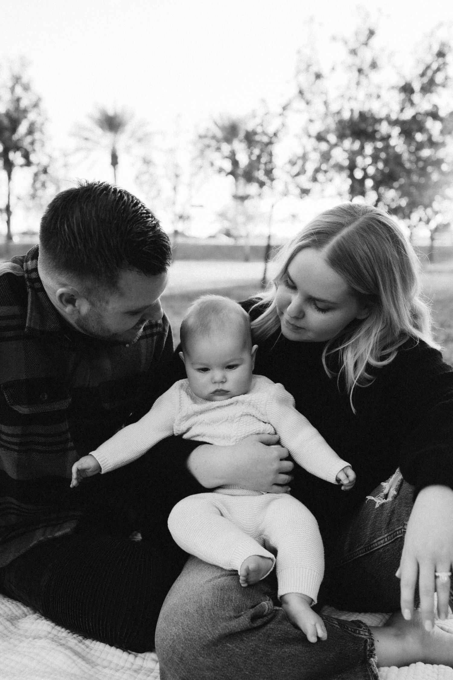 Family sharing intimate moment together on picnic blanket outdoors.