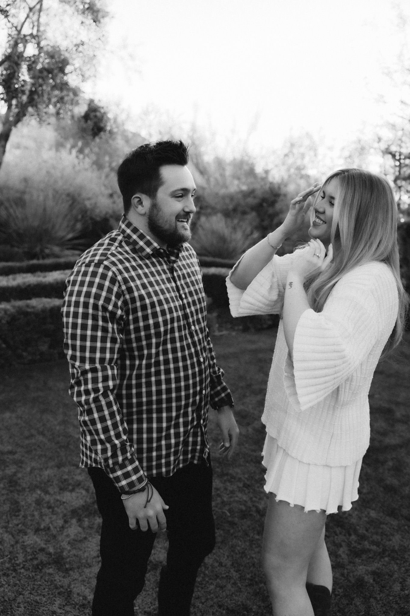 Candid moment between couple laughing together in garden setting.