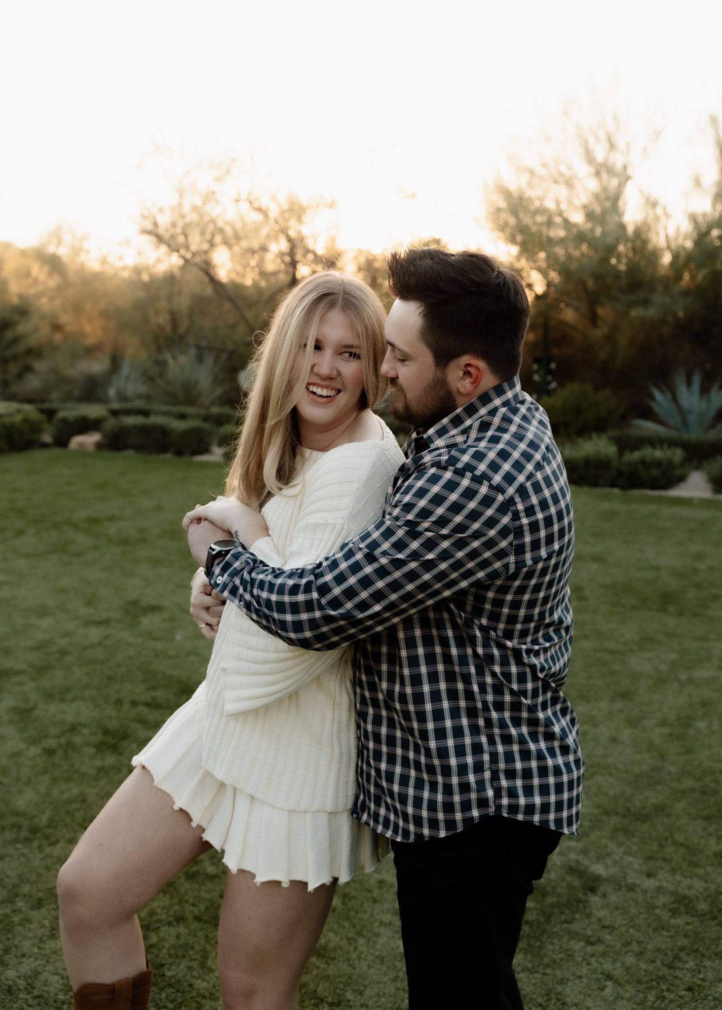 Playful moment captured between couple in garden setting during golden hour.