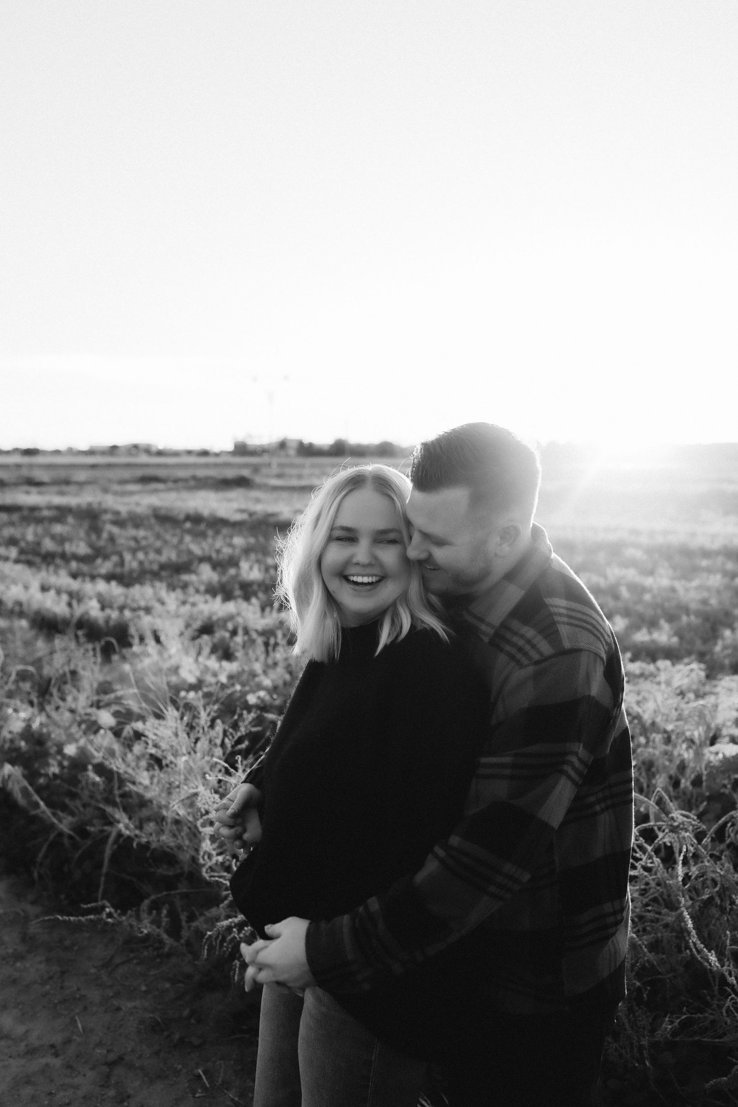 A joyful couple shares a candid moment together in black and white photography.