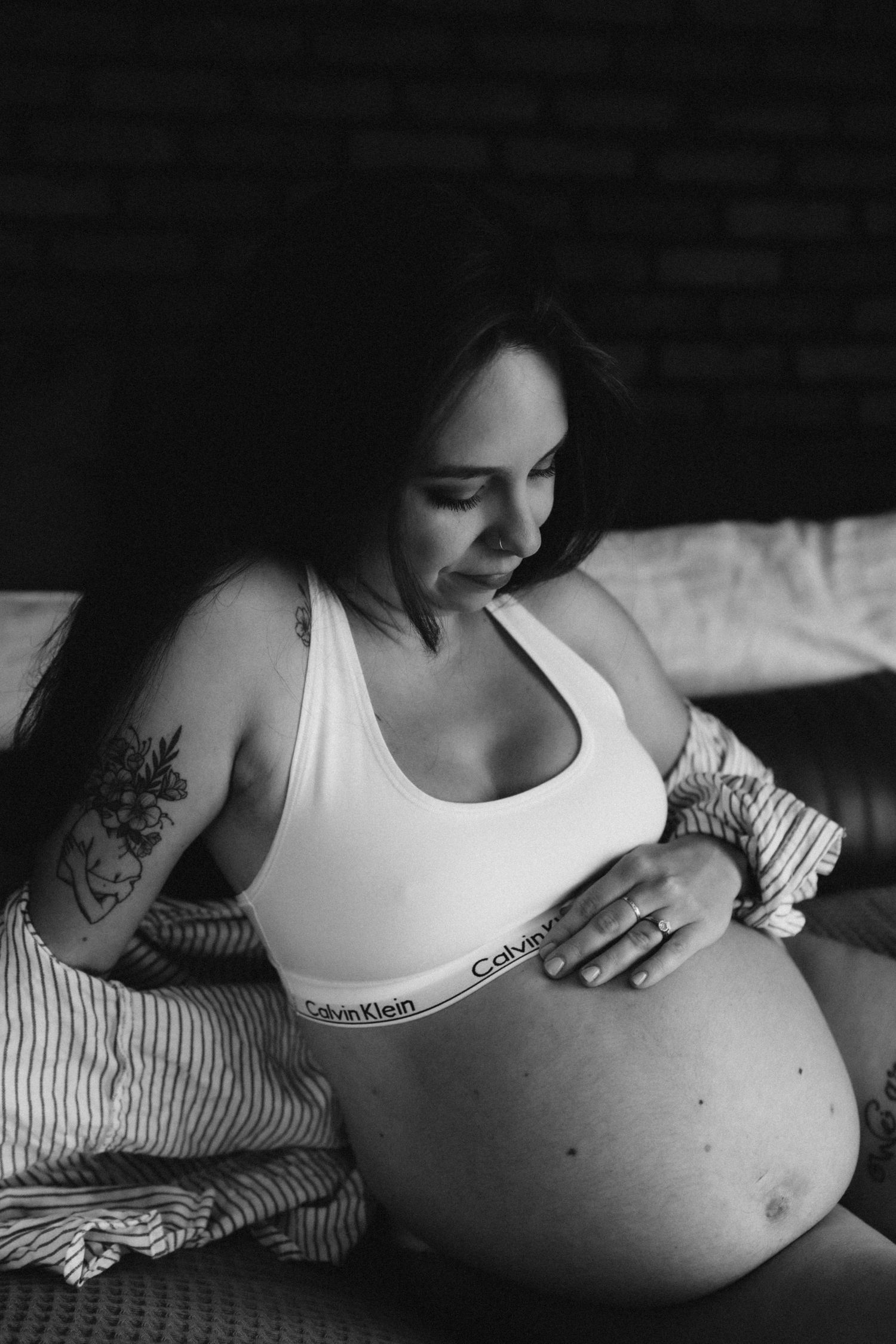 Intimate black and white photo of expectant mother in white tank top.