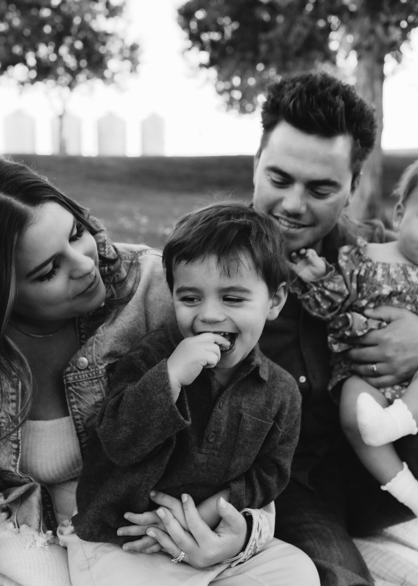 Casual outdoor family portrait with urban skyline visible in background.