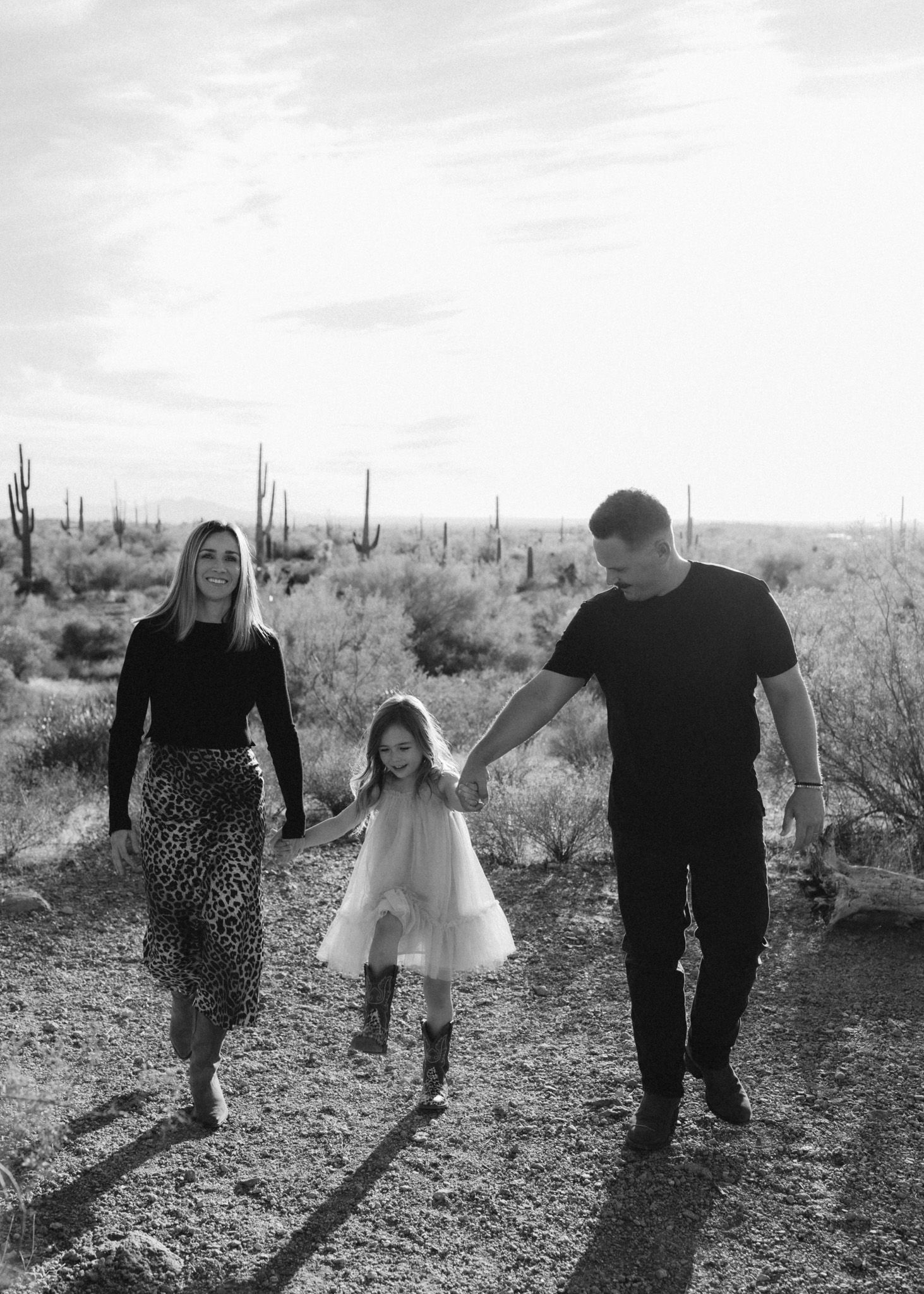 Family walking together through a desert landscape with saguaro cacti in the background.