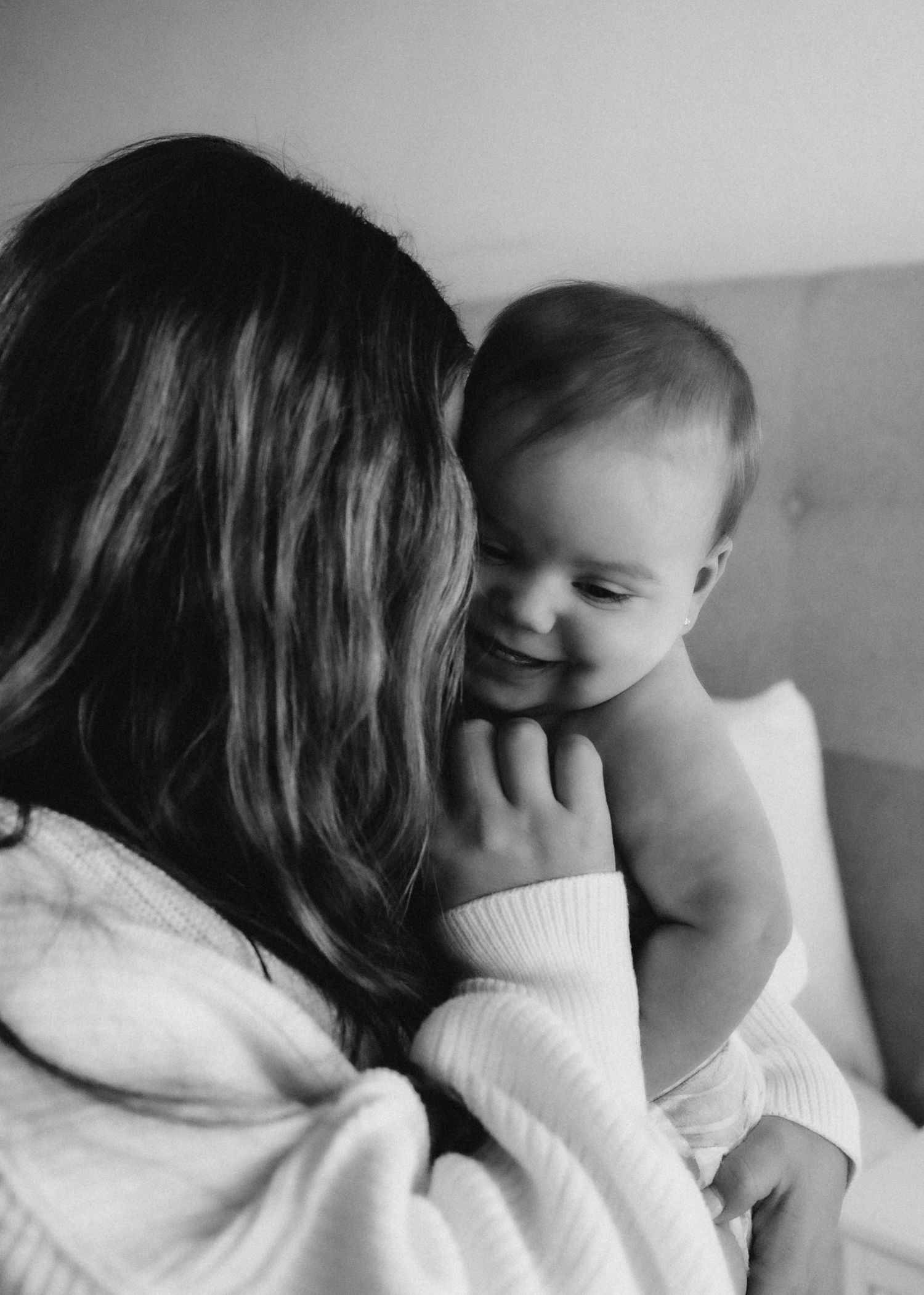 Intimate black and white portrait capturing a sweet moment between parent and smiling baby.