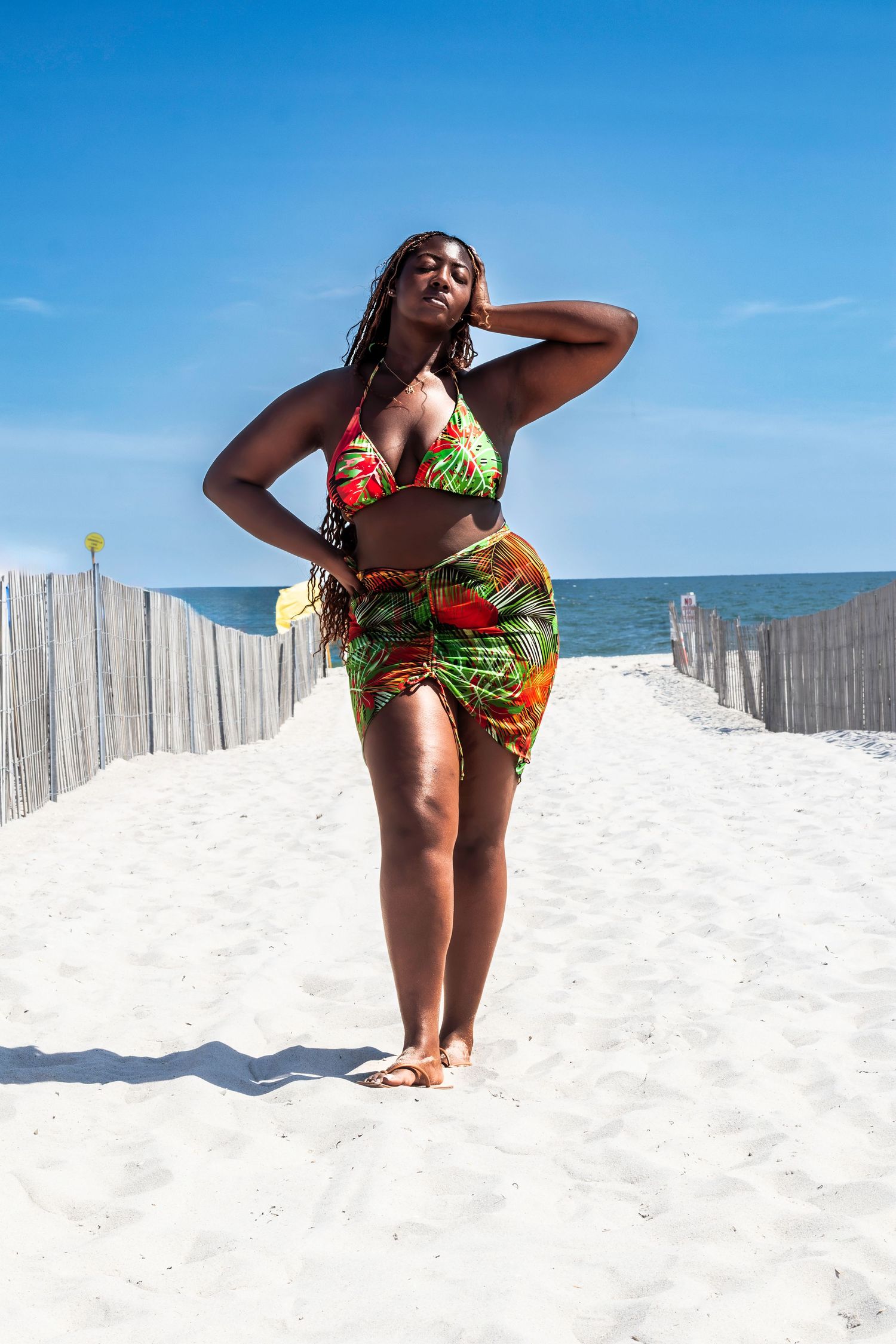 Summer beach portrait in colorful swimwear and wrap standing on white sand path.
