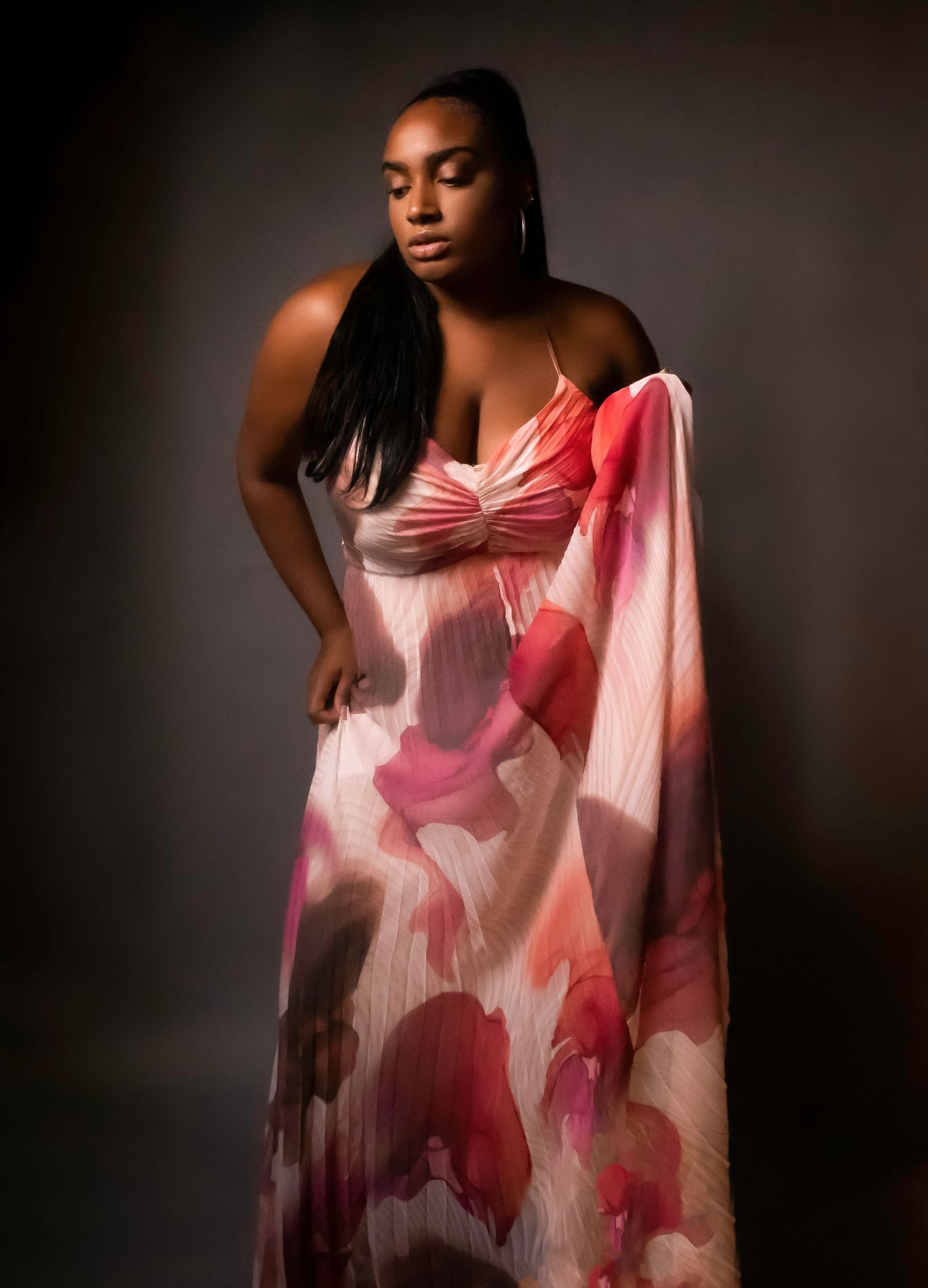 Artistic fashion portrait featuring a pink and white flowing dress against moody dark background.