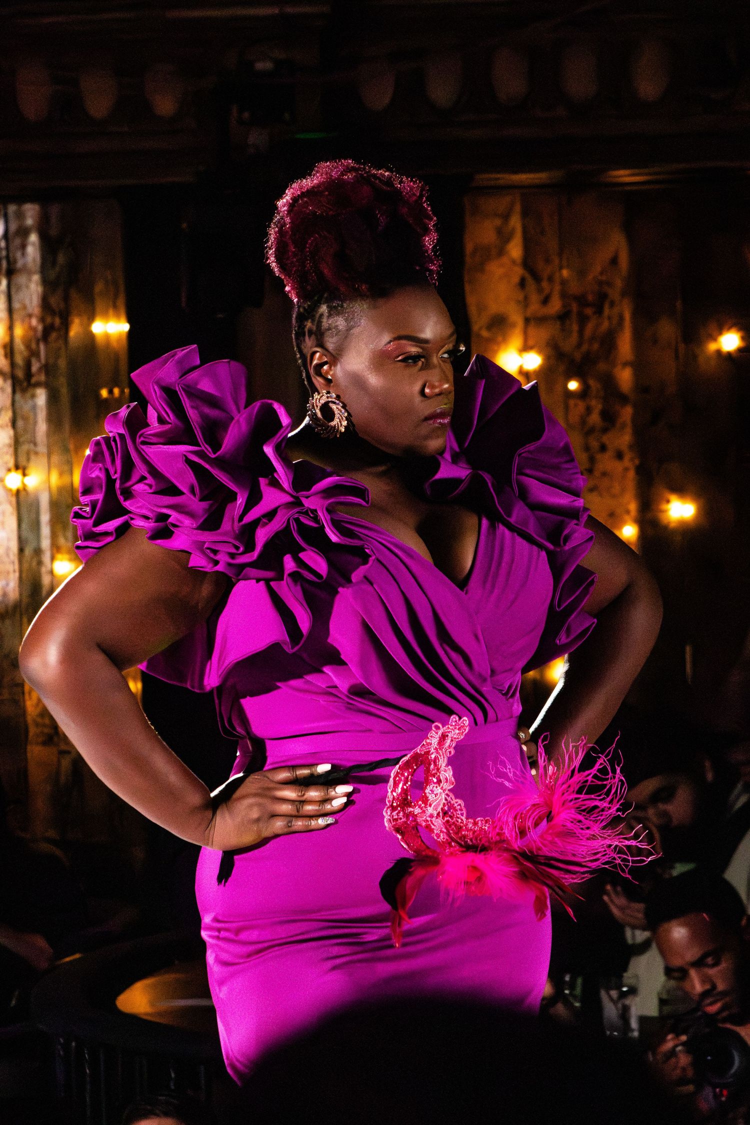 Model strikes pose in dramatic fuchsia ruffled gown during evening fashion show.