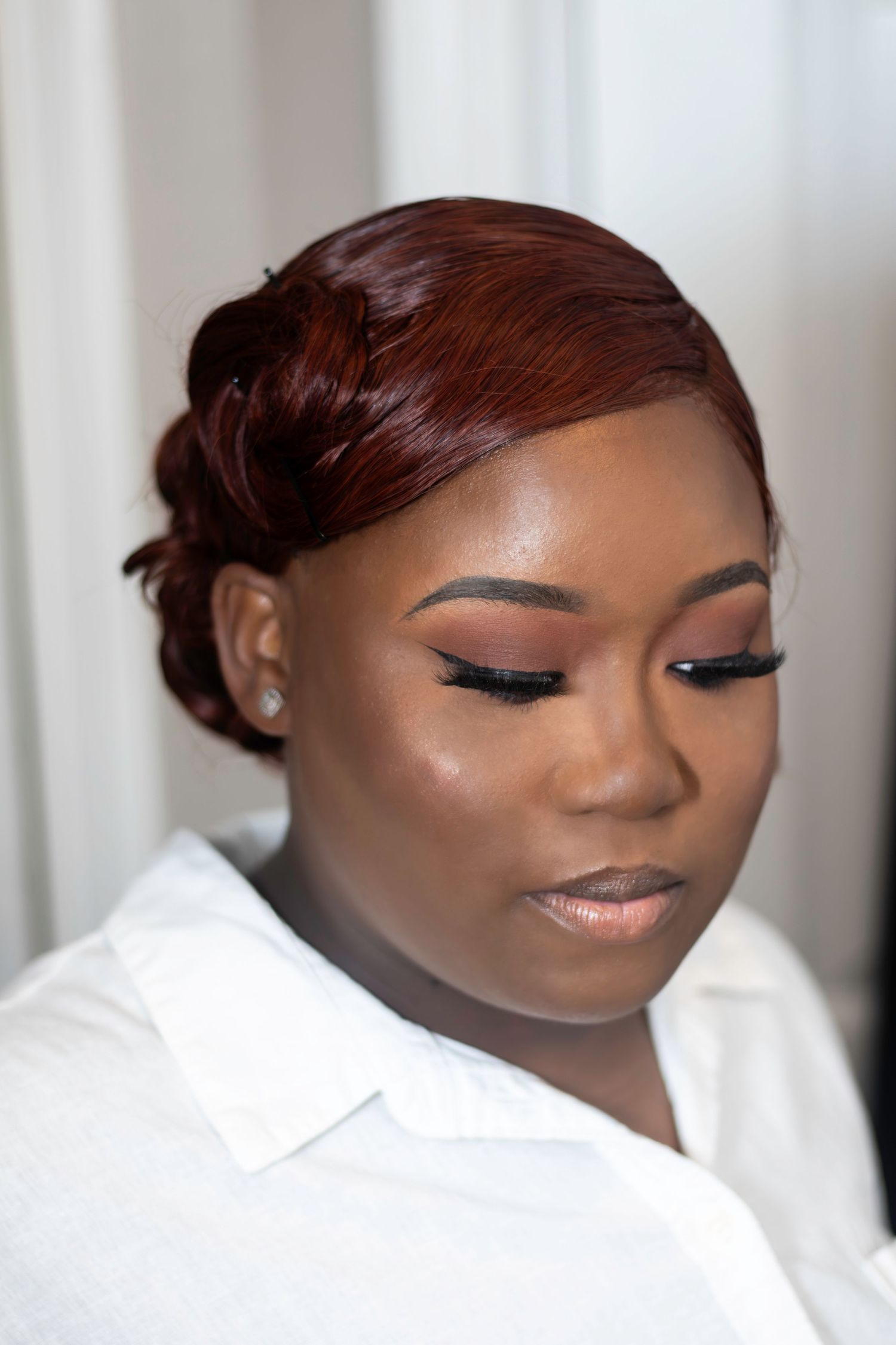 Elegant makeup look with sleek updo hairstyle and flawless complexion.