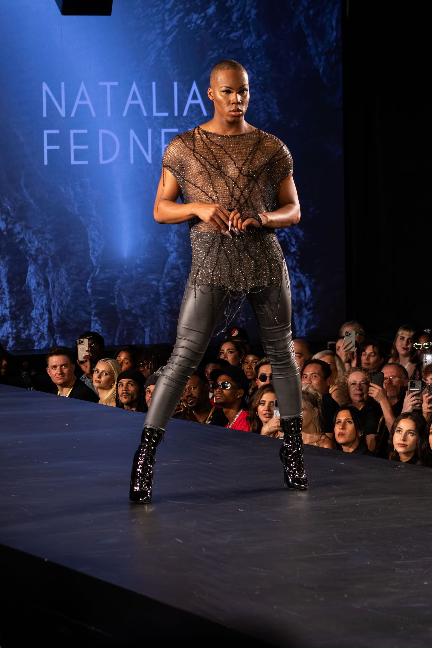 Model walks Natalia Fedner runway in sheer beaded top and leather pants with black boots.
