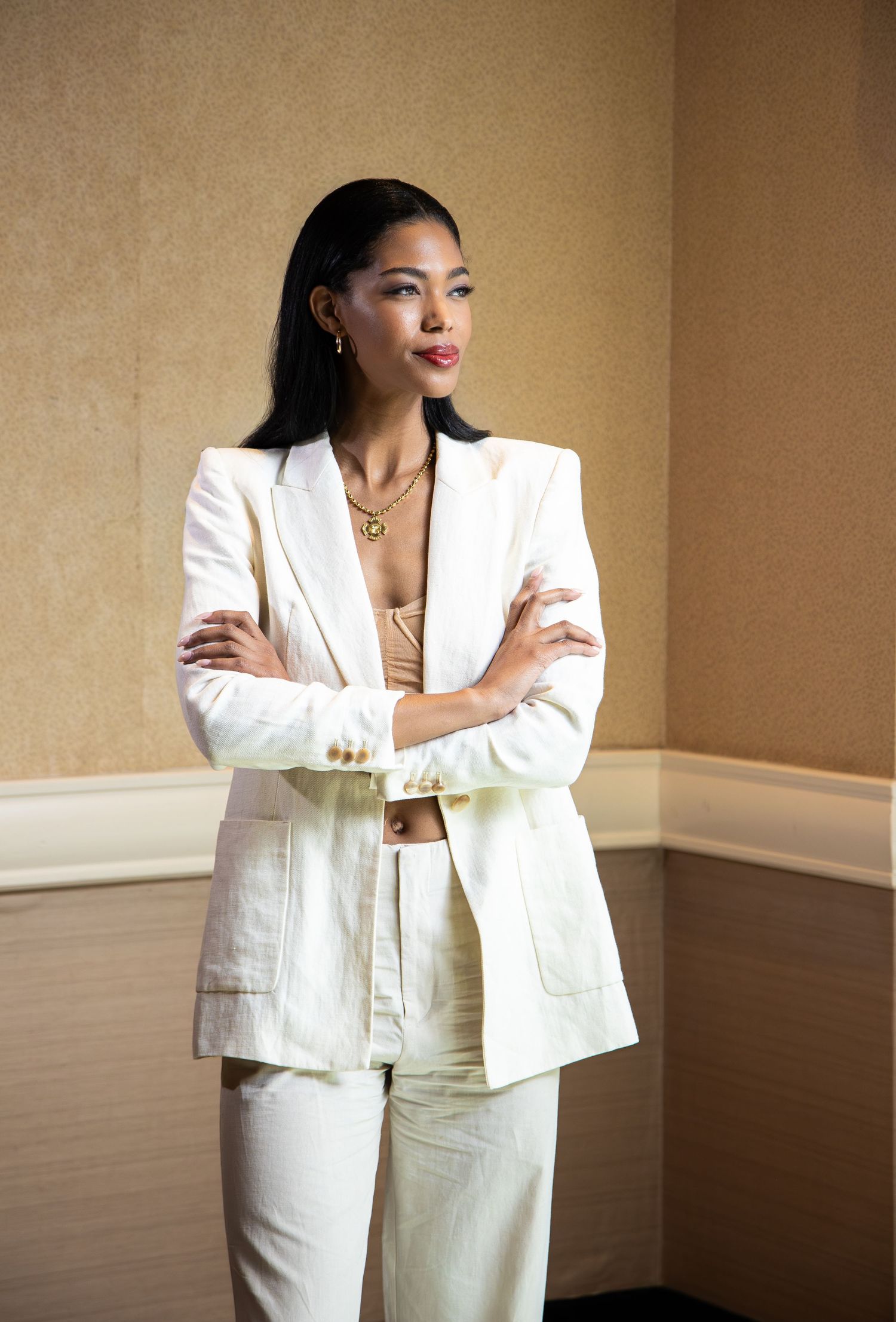 A series of fashion photos showing someone wearing an elegant white blazer suit against a beige wall.