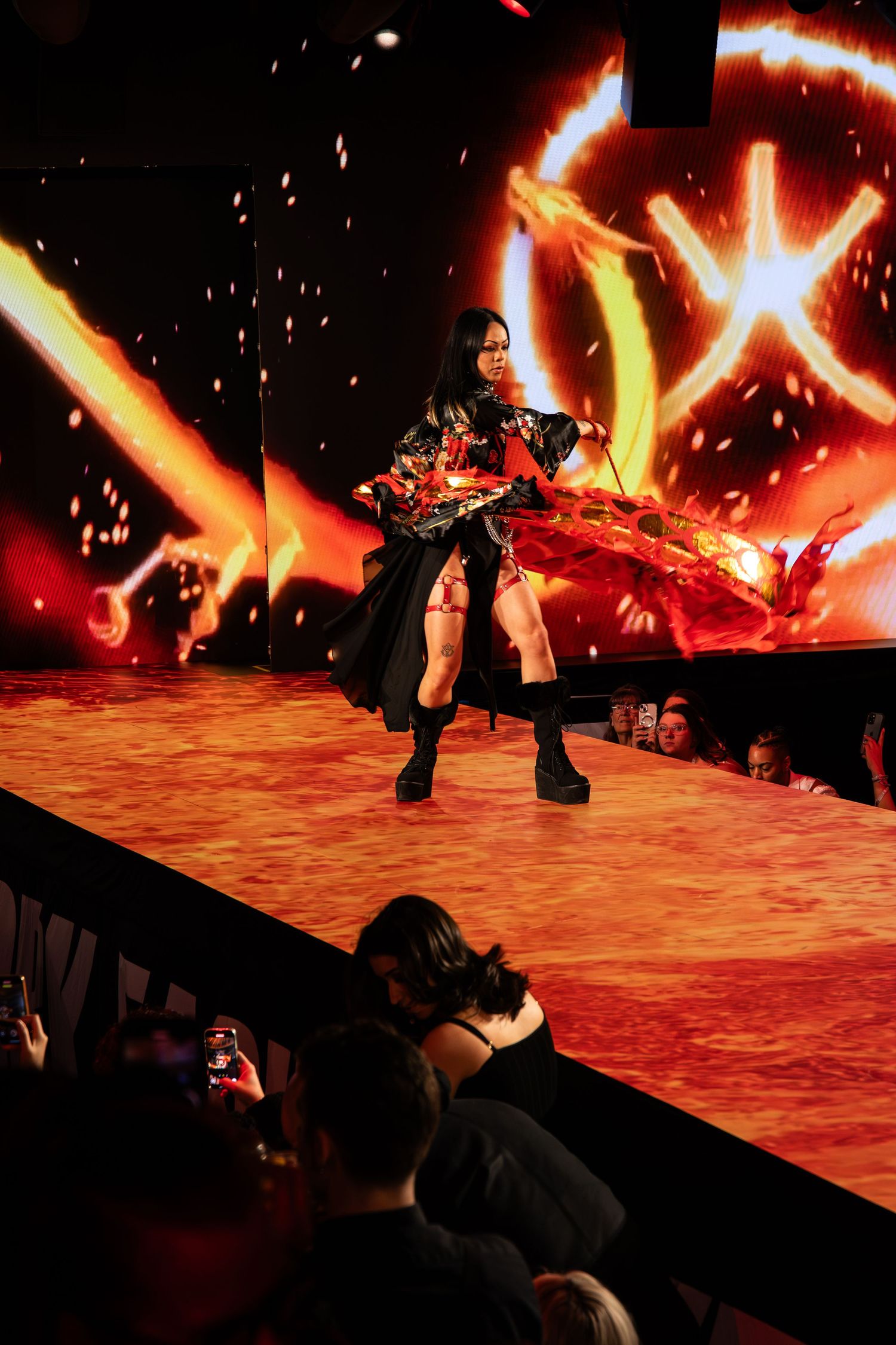 A performer wearing dark clothing dances on a stage with dramatic red lighting and star effects in the background.