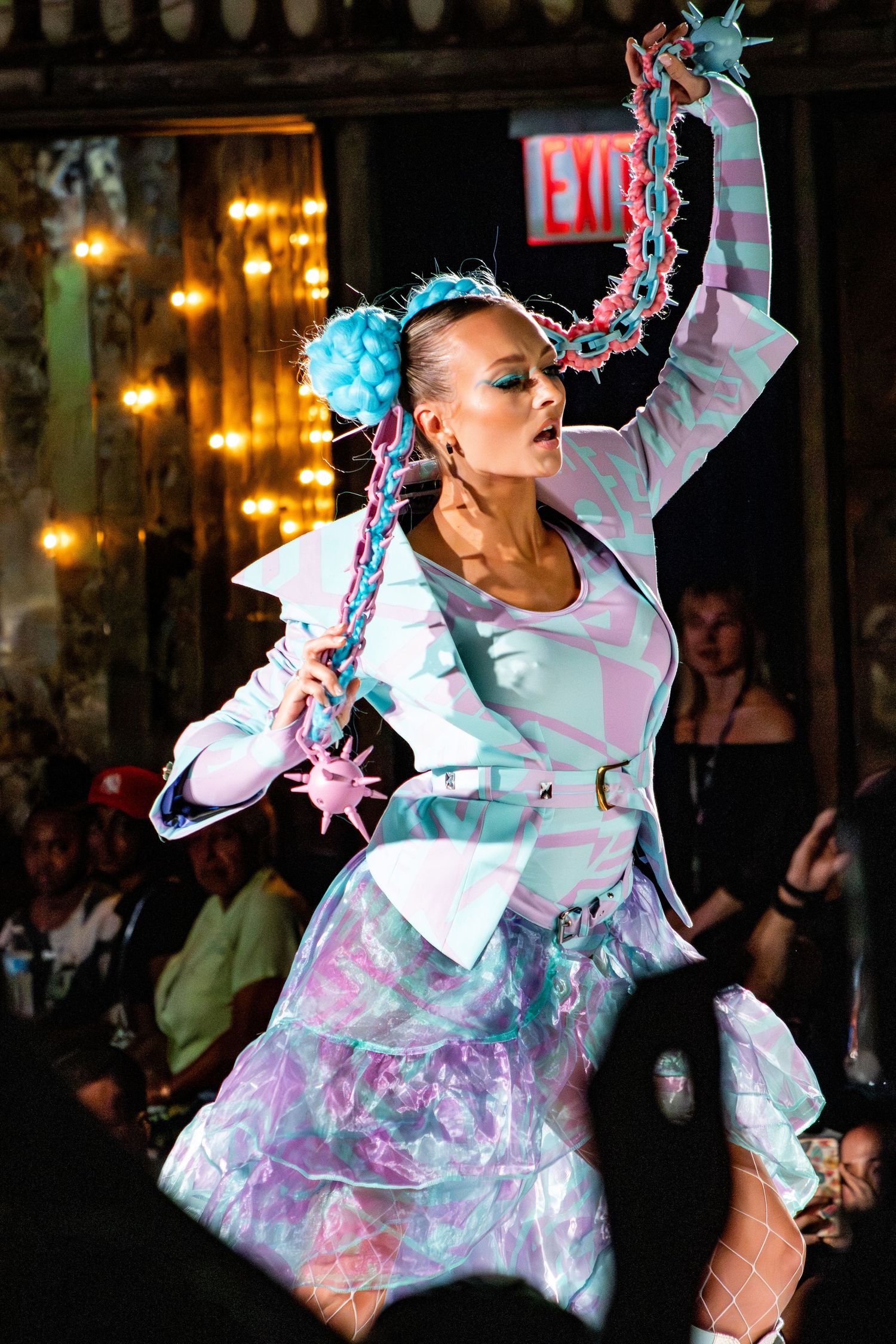 Dancer in white and blue ruffled costume with matching hair accessories performs on stage.