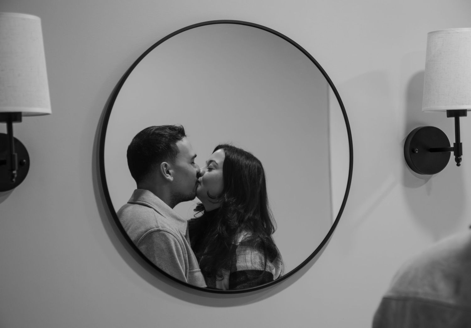 A black and white photo sequence showing a couple kissing in front of an oval mirror.