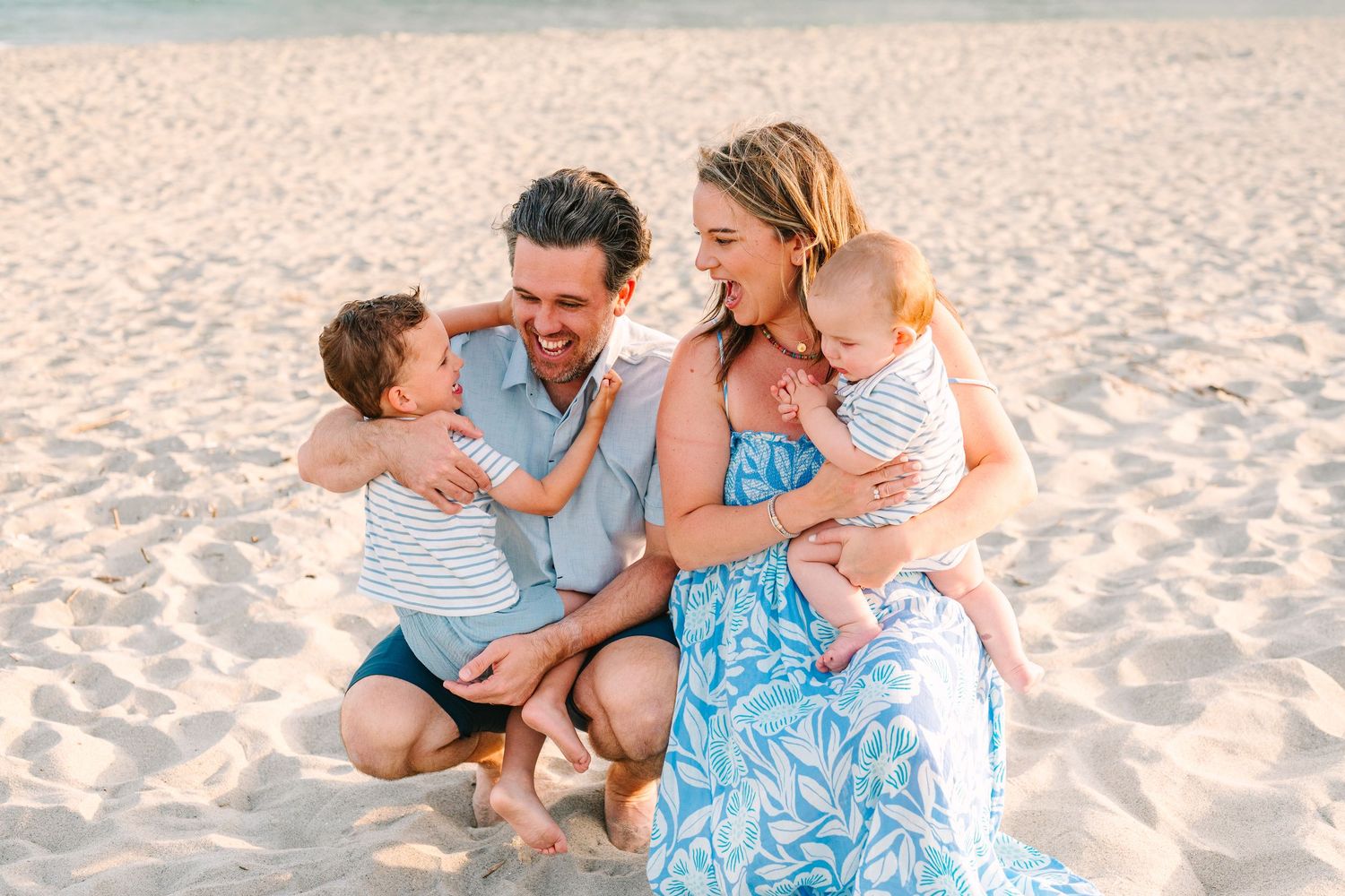 Family enjoying a tender moment together on a sandy beach at sunset.