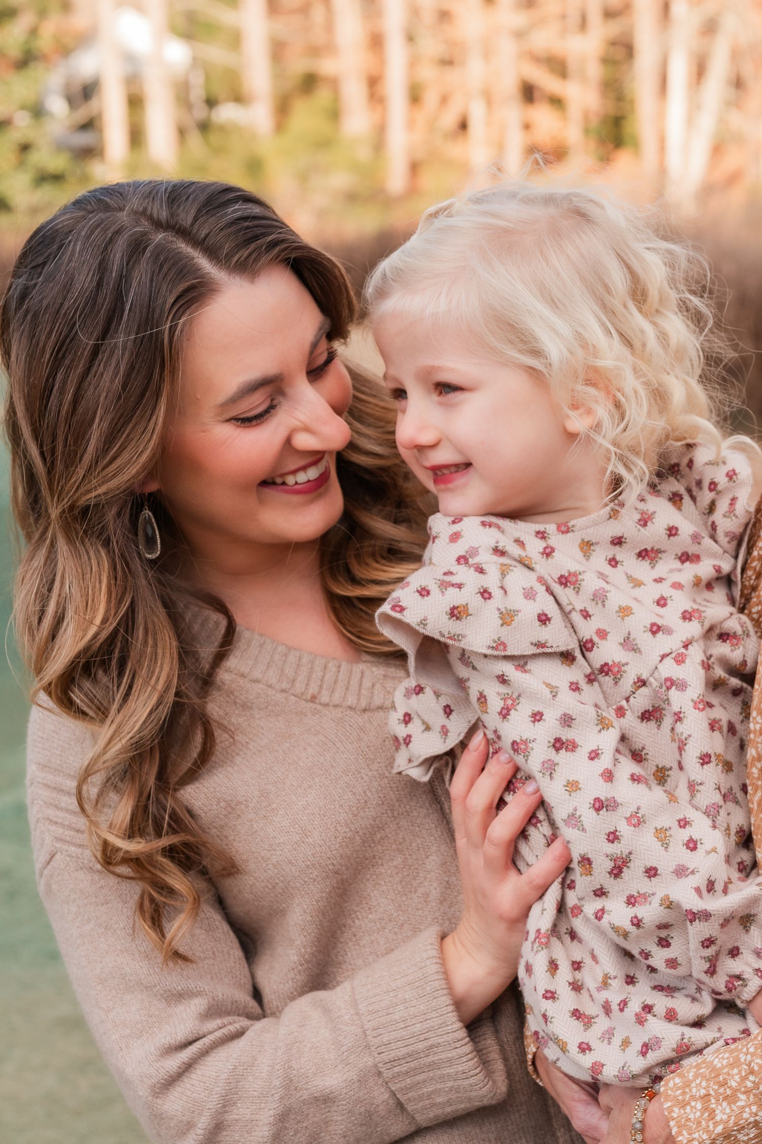 Sweet candid moment between a woman and young child outdoors in autumn lighting.