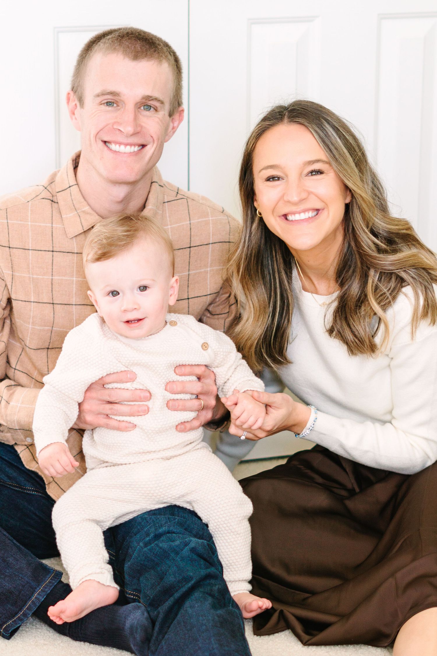 Family portrait showing happy trio in coordinated casual outfits.