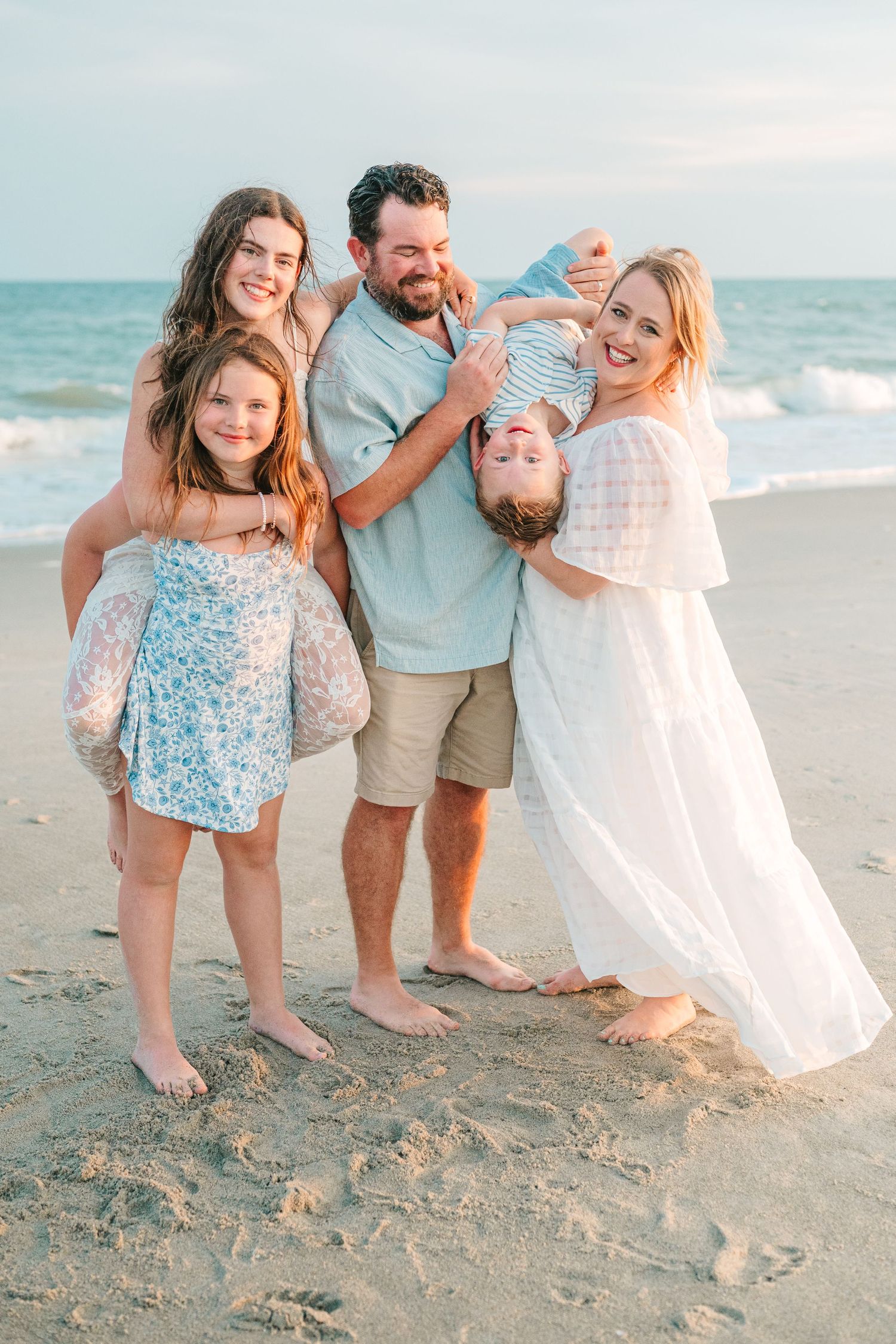 Family having fun and playing together during sunset beach photoshoot.