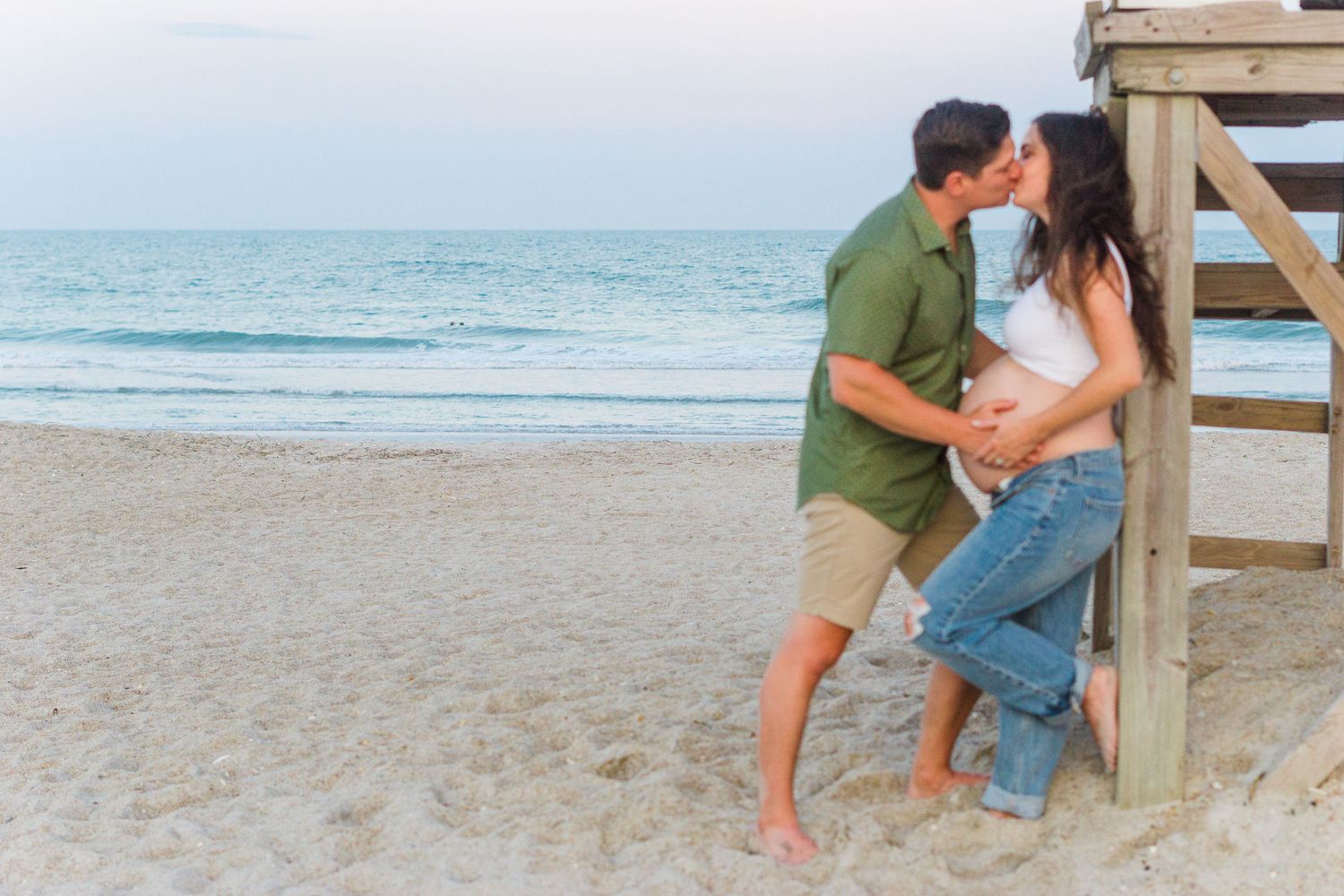 A tender beachside moment captured during a maternity photo session.
