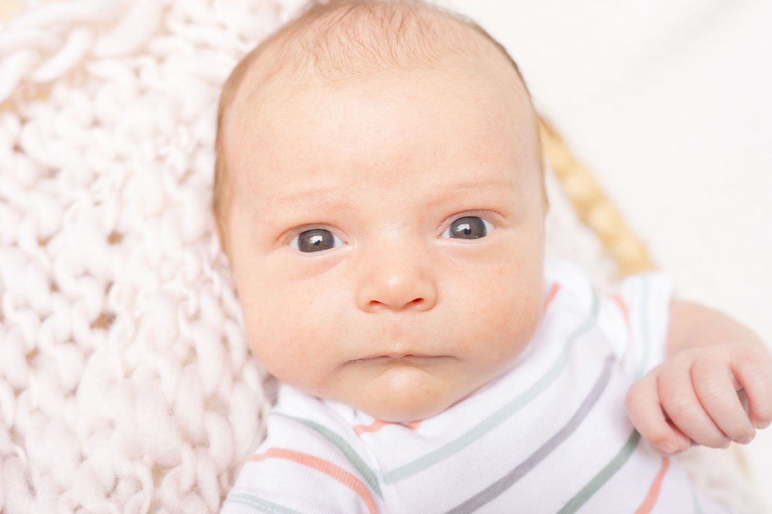 Close-up of infant with bright eyes wearing striped onesie.