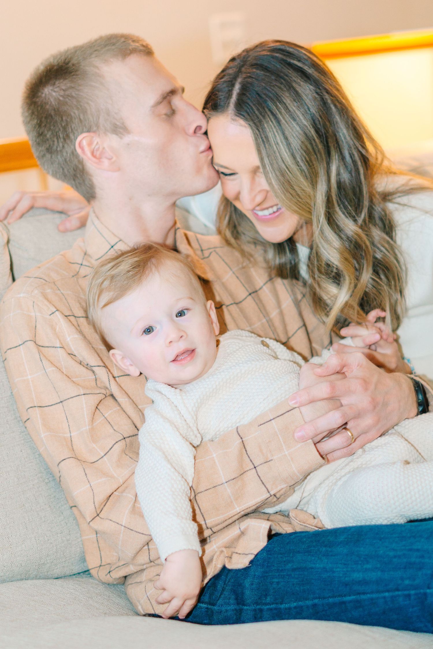 An affectionate family moment captured on a comfortable gray couch.