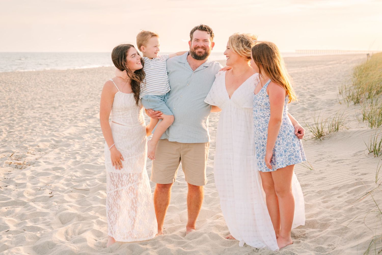 Extended family enjoying a joyful moment together on the beach at sunset.