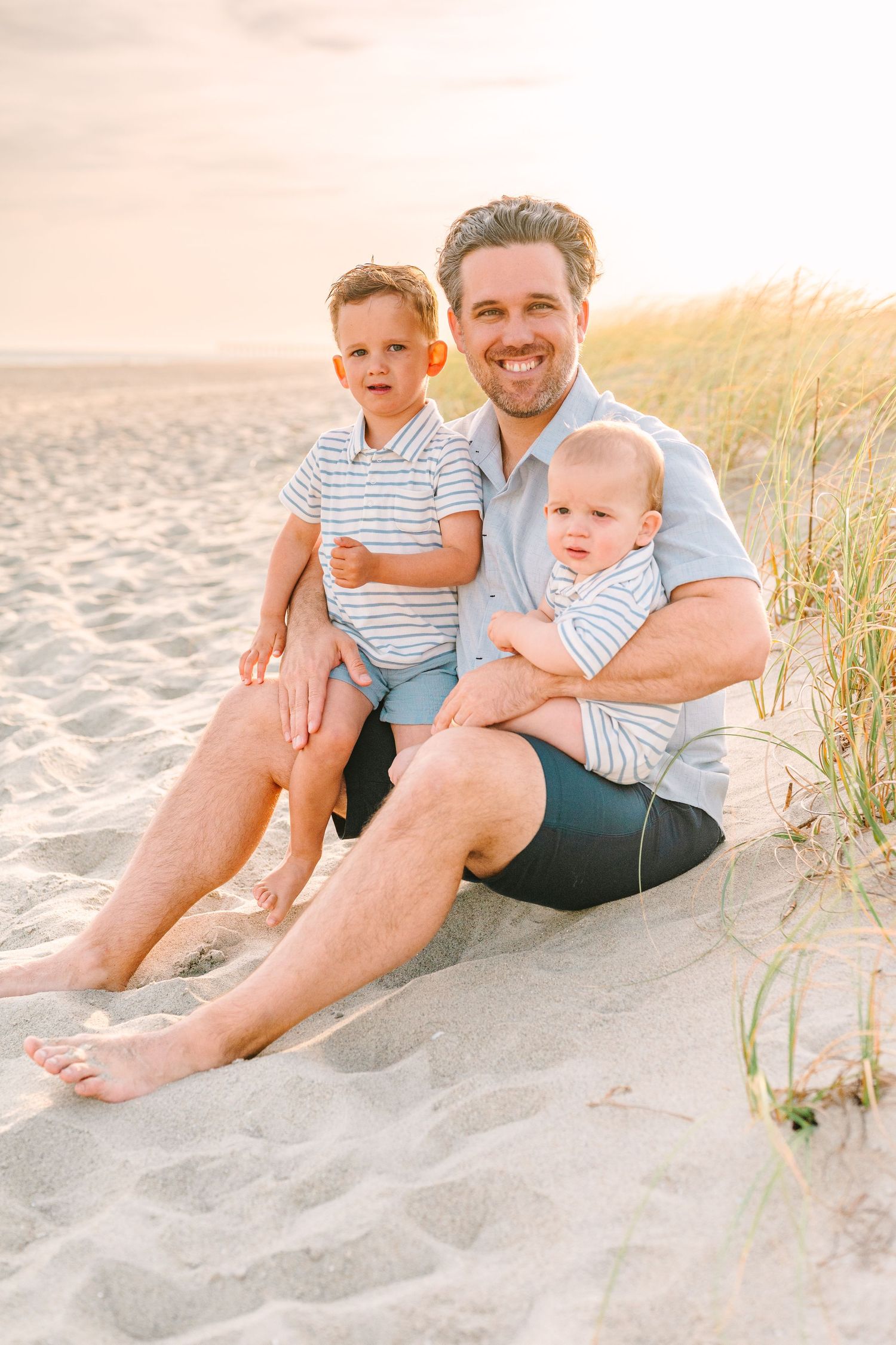 A heartwarming beach portrait with children on sandy dunes during golden hour.