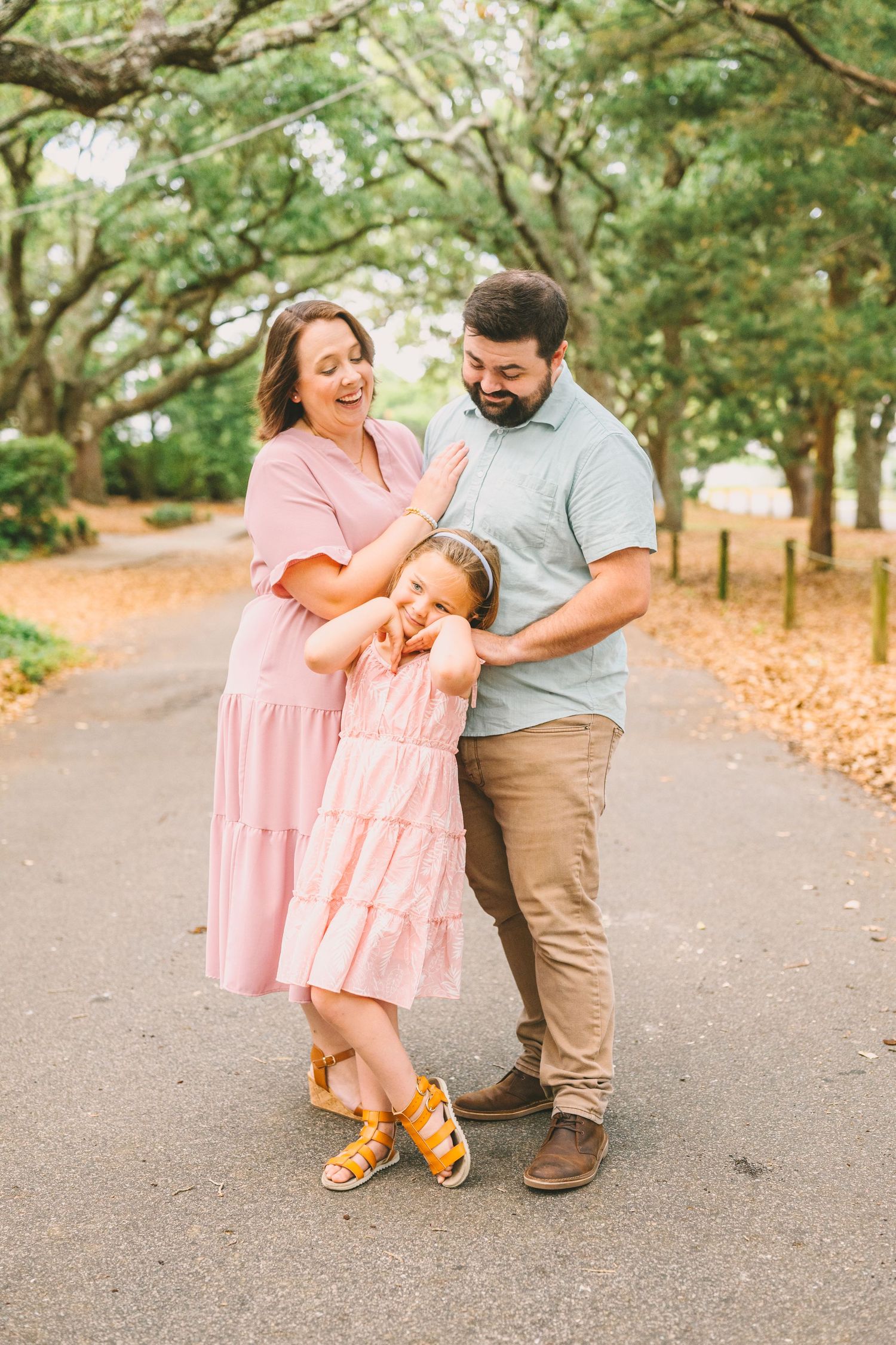 A joyful family shares a laugh together while posing on an autumn path.