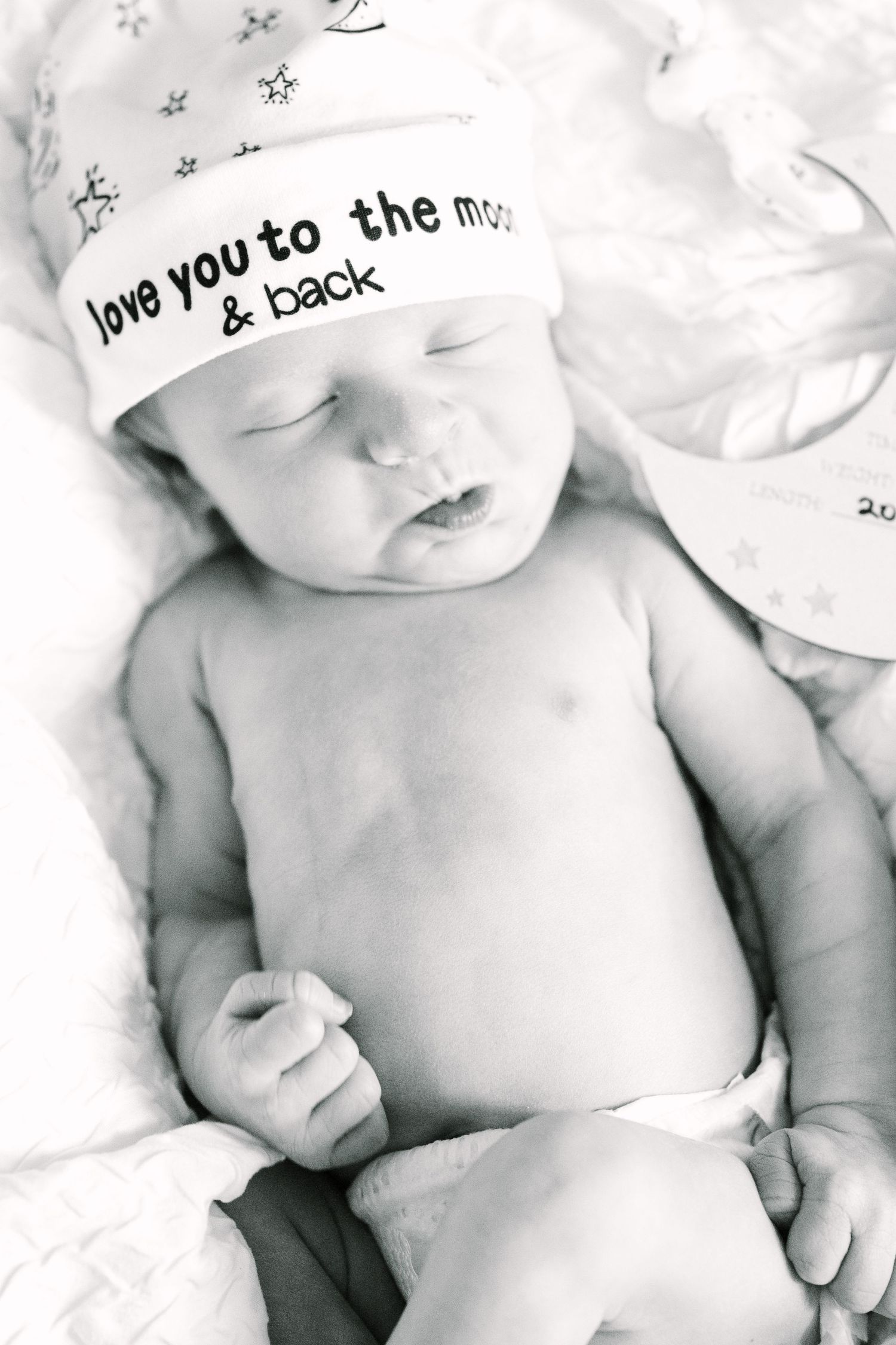Black and white photo of newborn baby wearing hat with text 