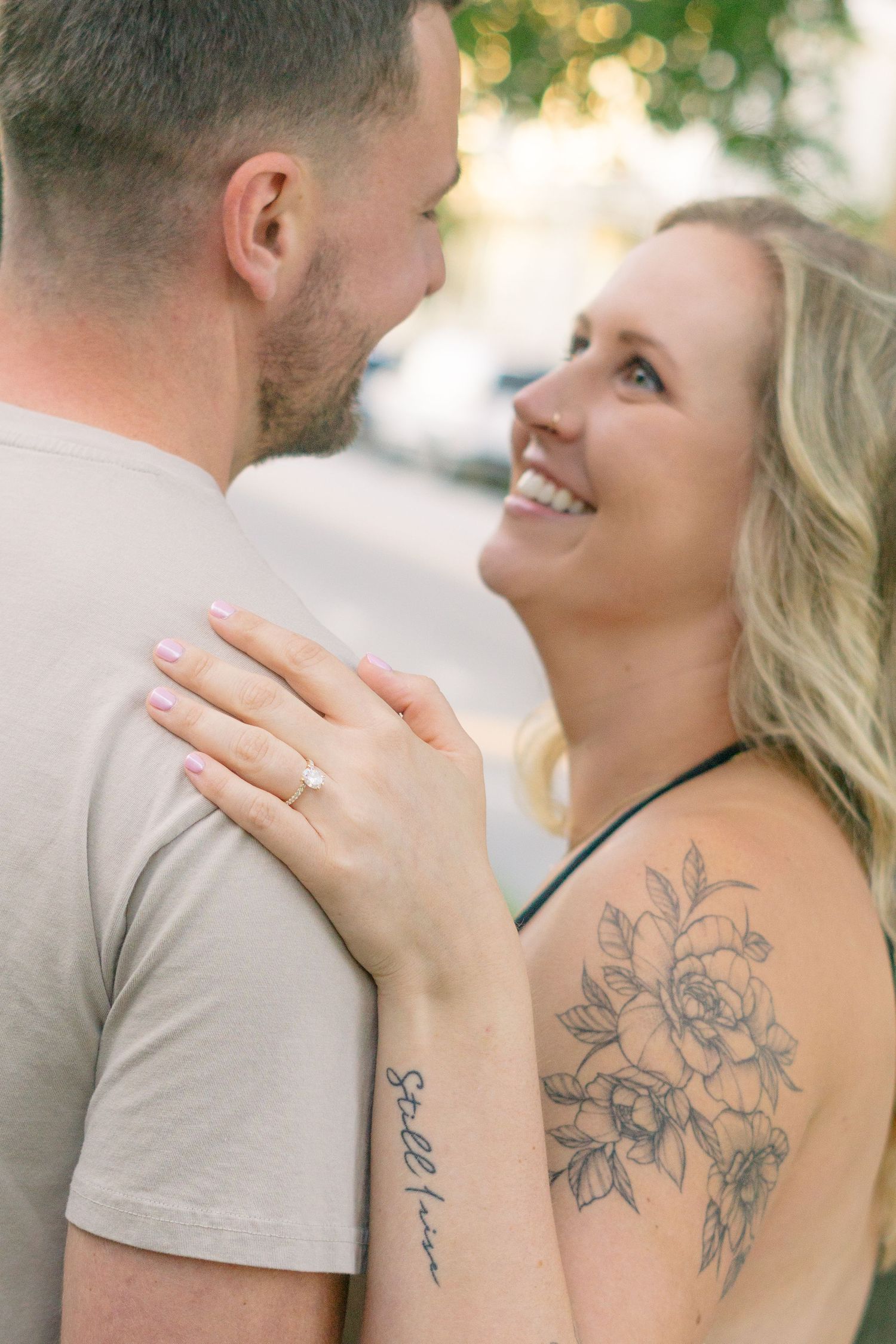 Close-up of couple sharing an intimate moment outdoors with visible floral tattoo.