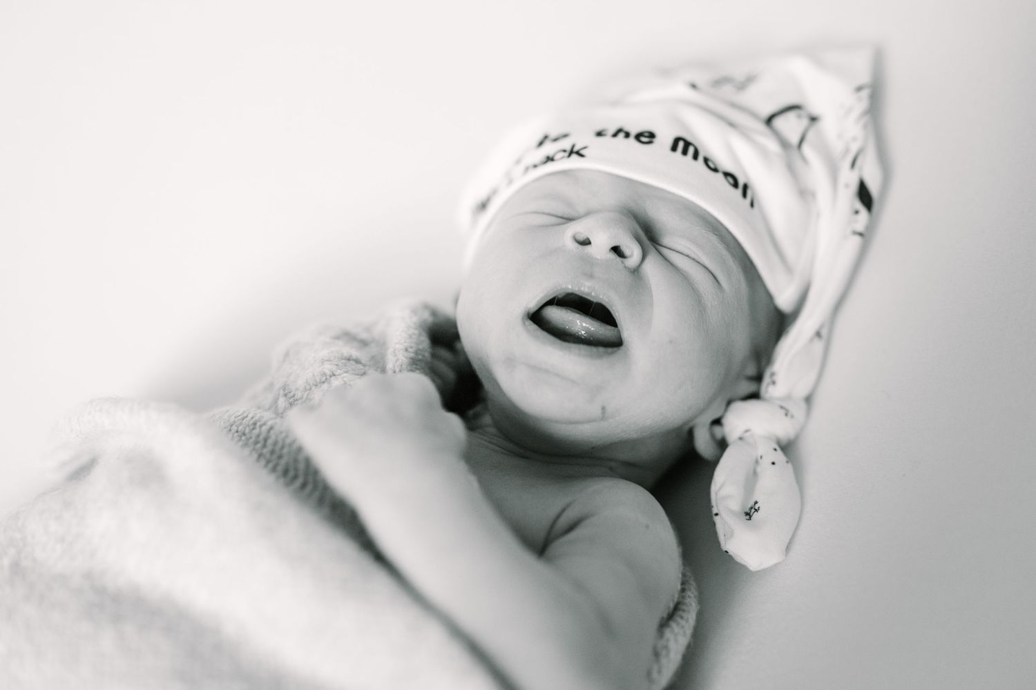 High contrast black and white portrait of peaceful sleeping newborn wearing knit cap.