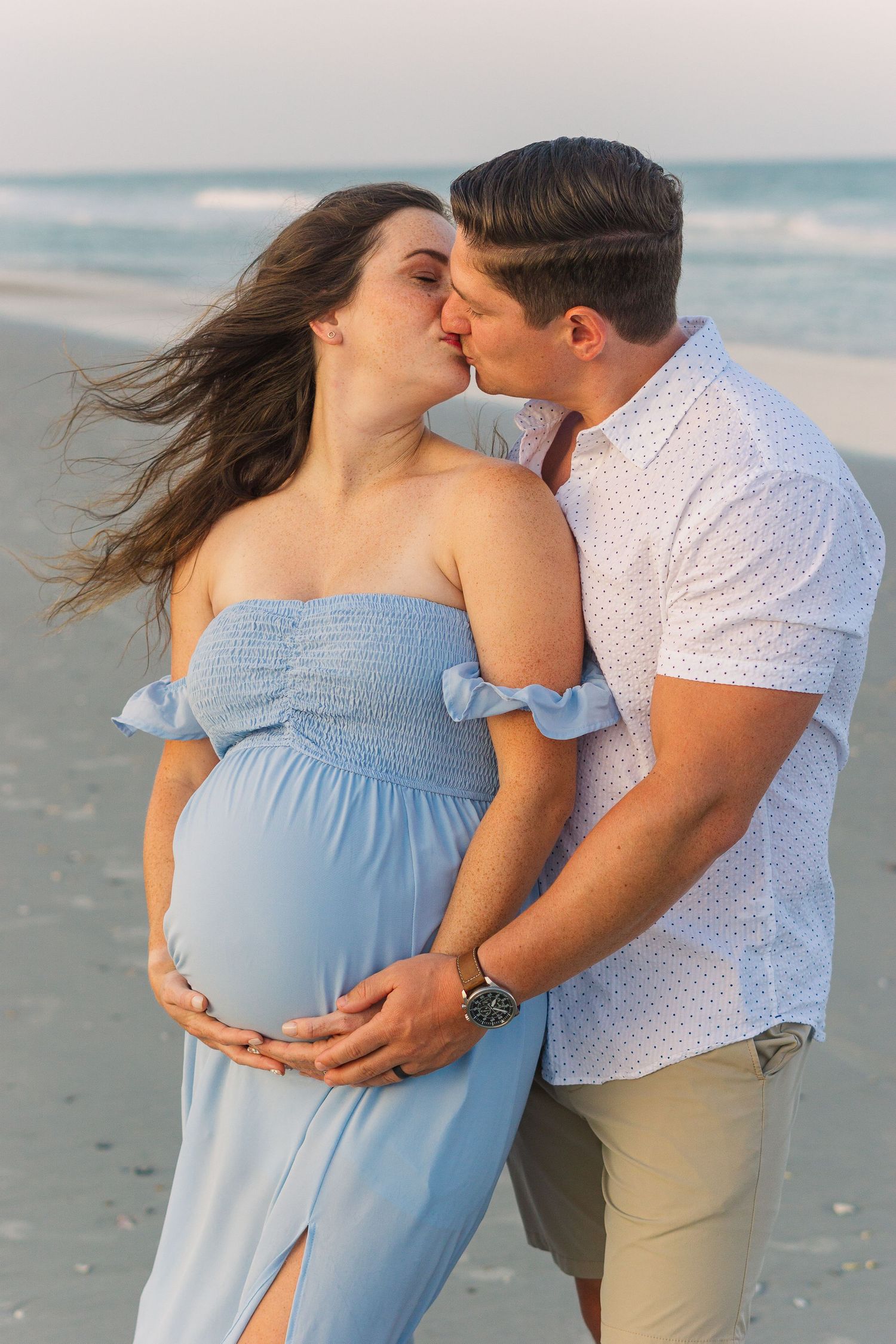 Romantic beach maternity photo showing an intimate moment between couple.