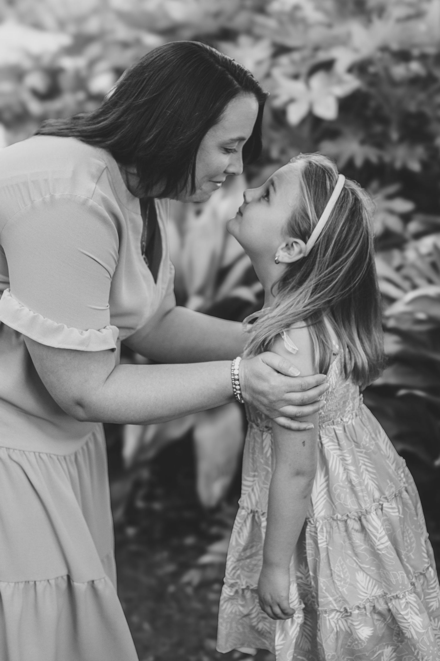 A tender moment captured in black and white as two people share an affectionate embrace in a garden setting.