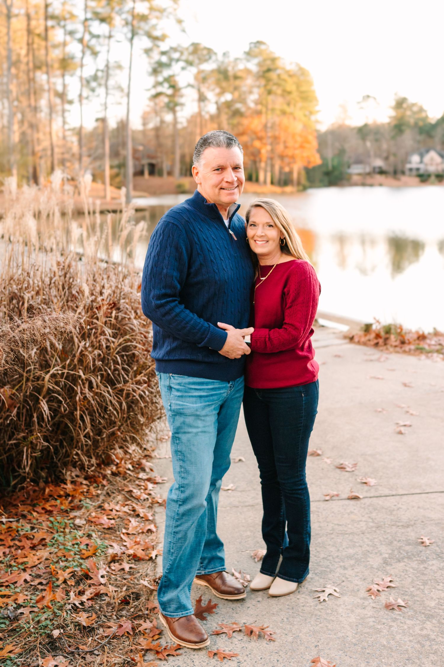 A couple shares an intimate moment by a lake during golden hour autumn light.