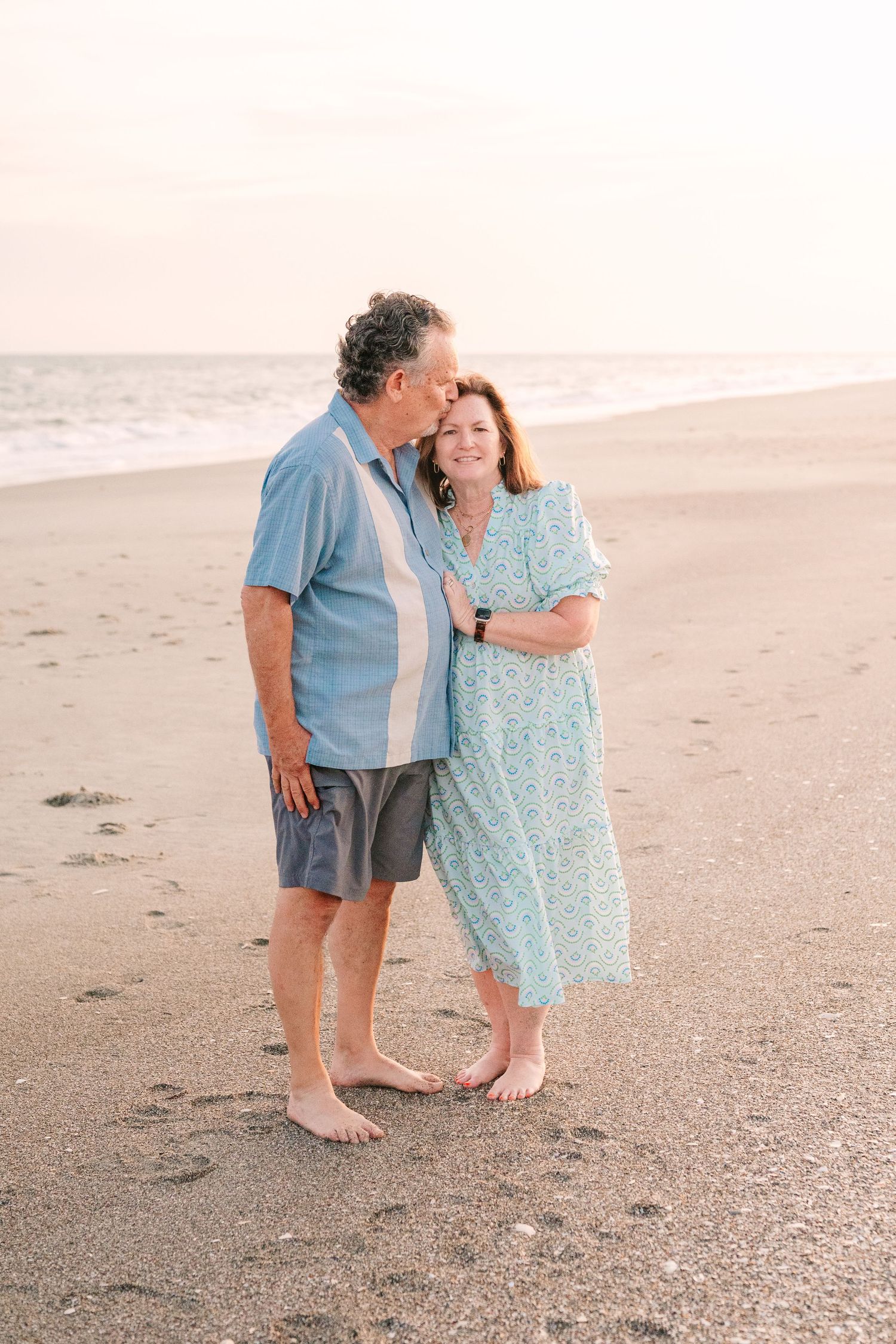 Couple sharing an intimate moment together on a serene beach at sunset.