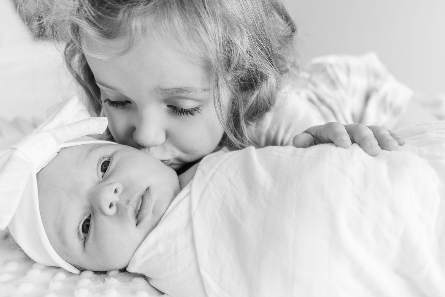 Black and white photo of siblings sharing tender moment.