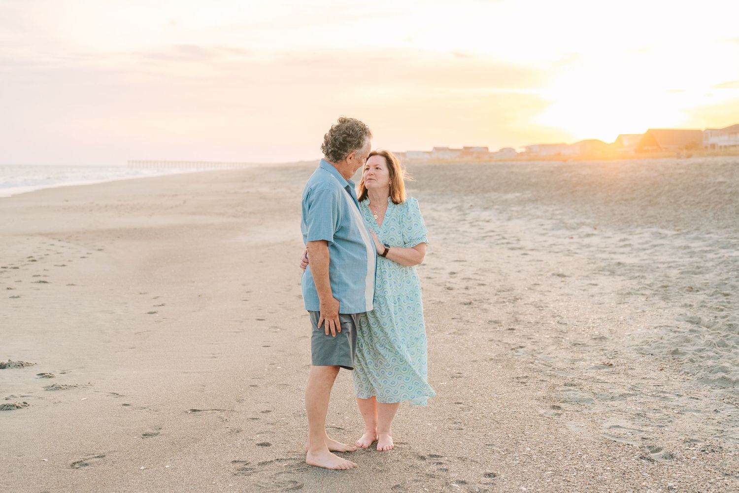 Romantic beach sunset portrait of couple walking along the shoreline.