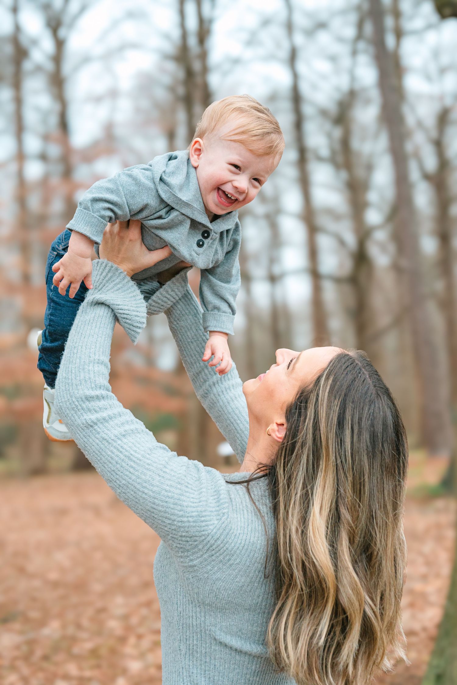 A joyful playtime moment in an autumn forest setting with soft knit sweaters and lots of laughter.