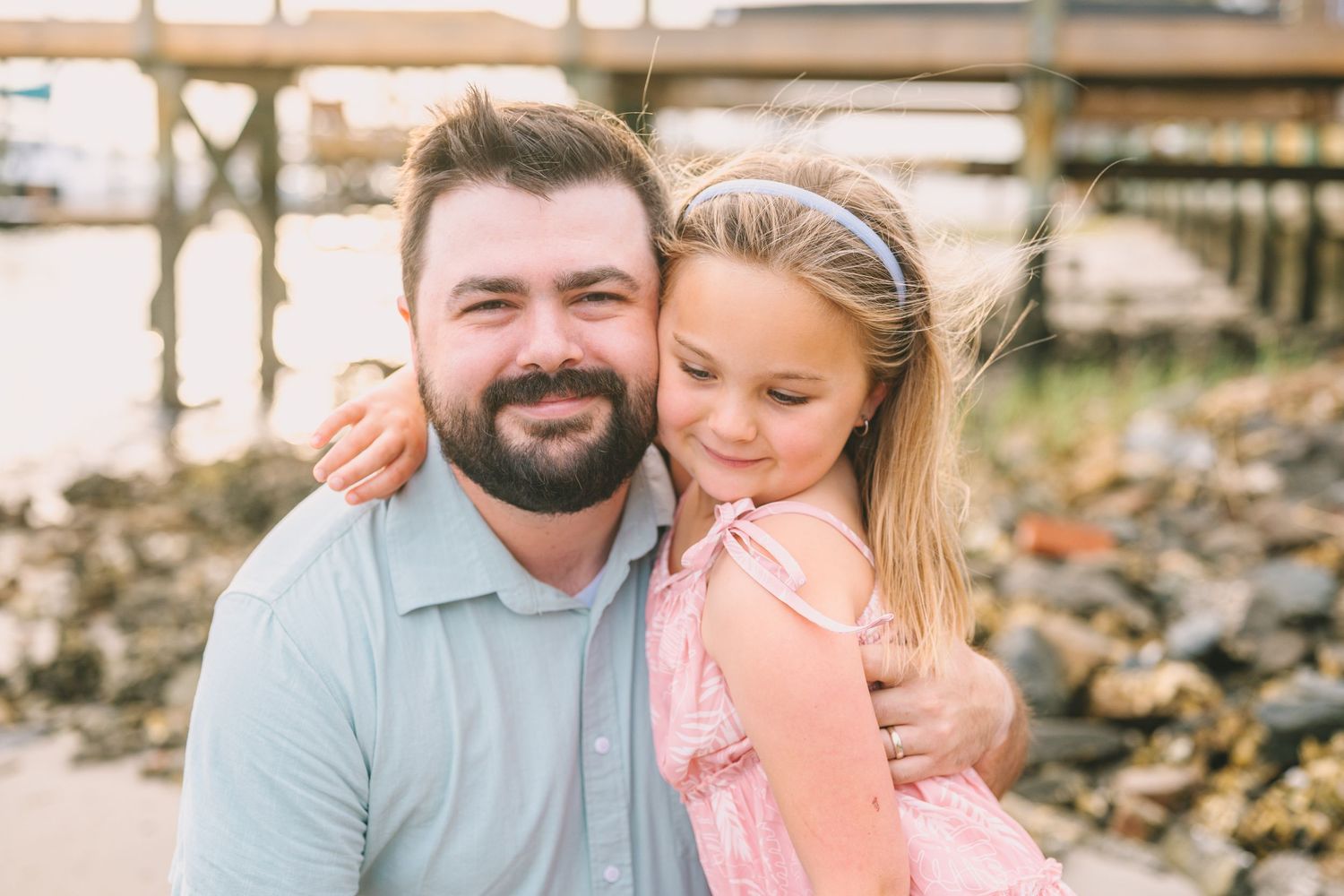 A heartwarming outdoor portrait of family members embracing by a rocky shoreline.