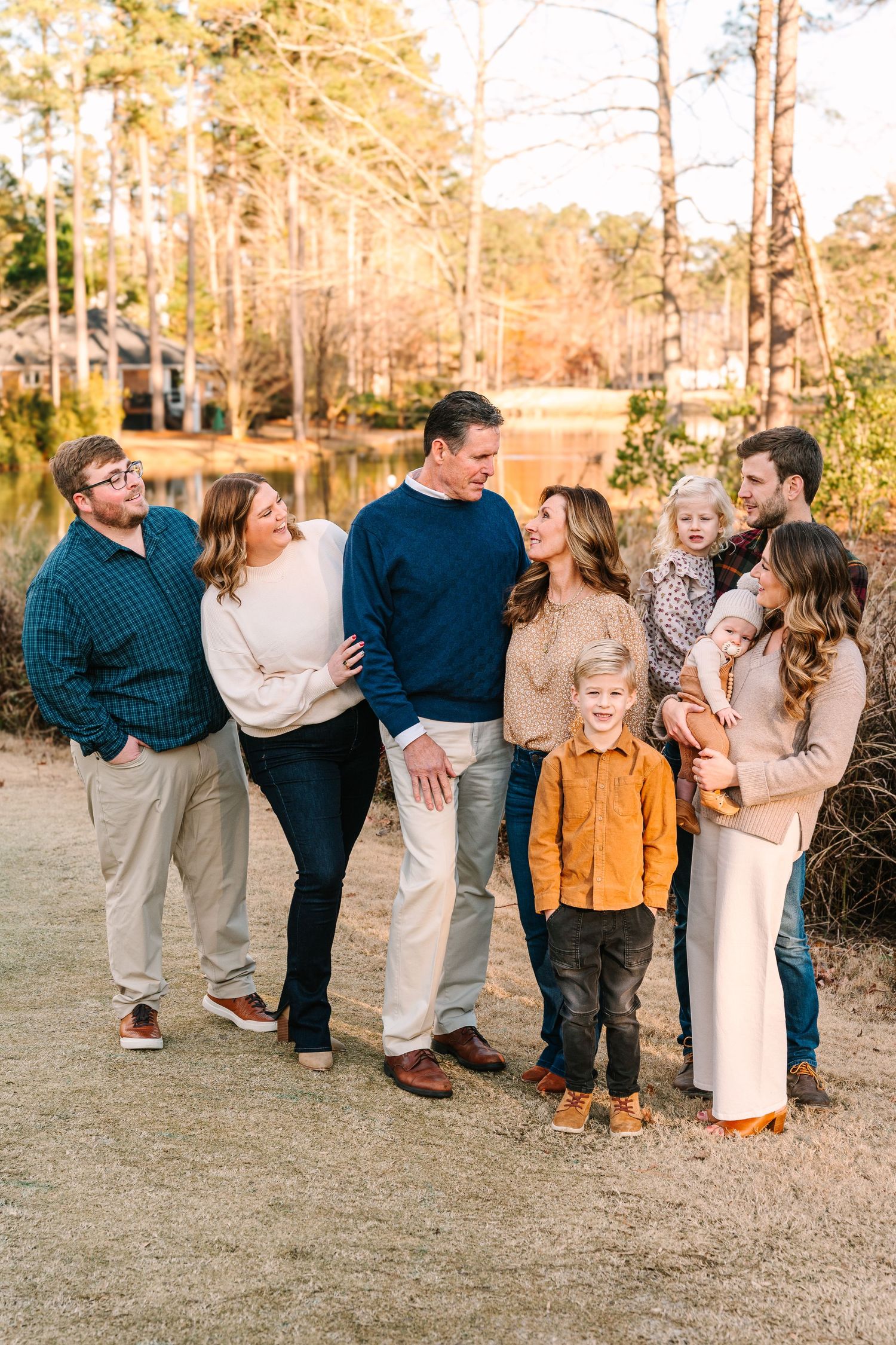 Casual family photo session on a path with golden sunlight filtering through trees in the background.