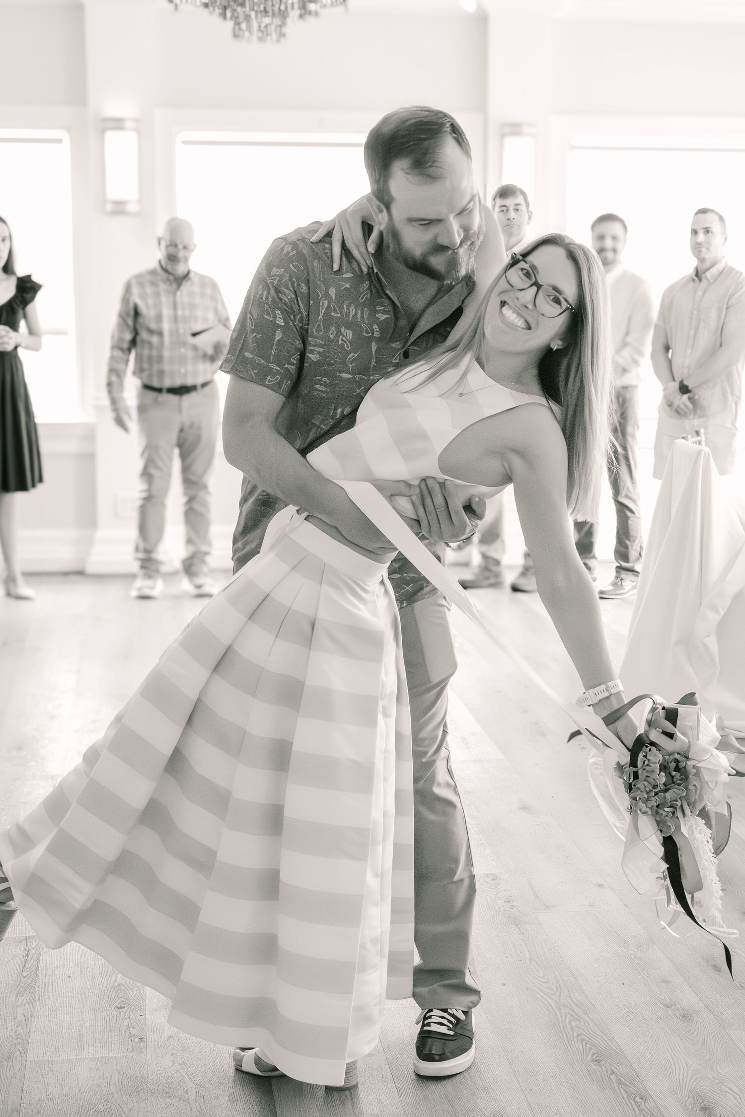 A romantic black and white dance photo showing a couple dipping during what appears to be a wedding reception.