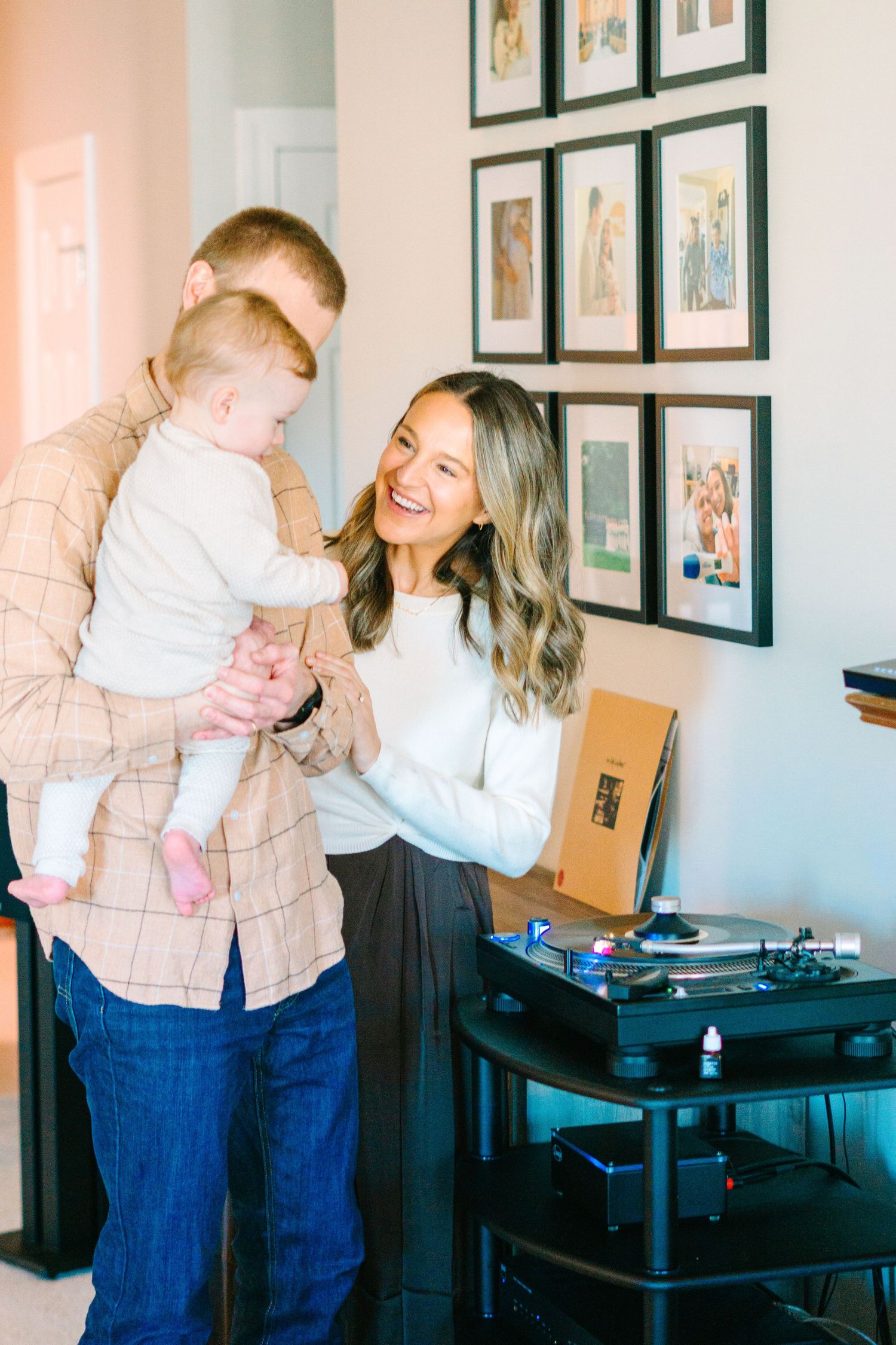 Family sharing joyful moment together near wall of framed photos and record player.