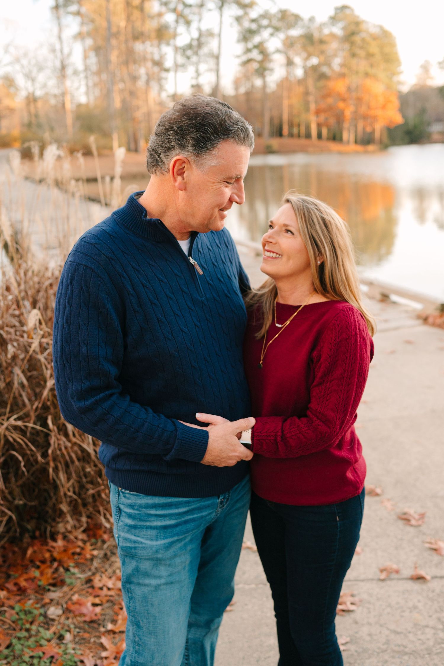 A couple shares a loving moment along a lakeside path during sunset.