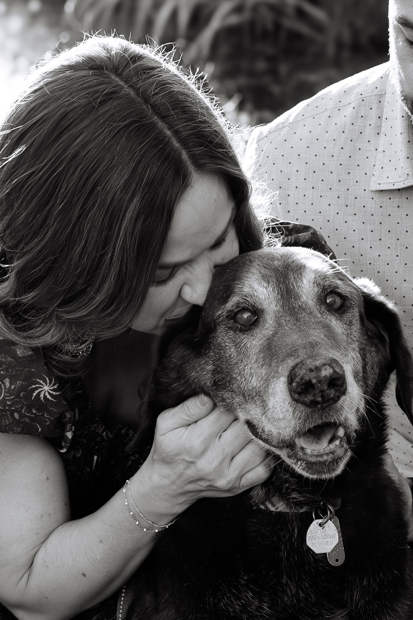 Black and white close-up of person sharing tender moment with their senior dog.