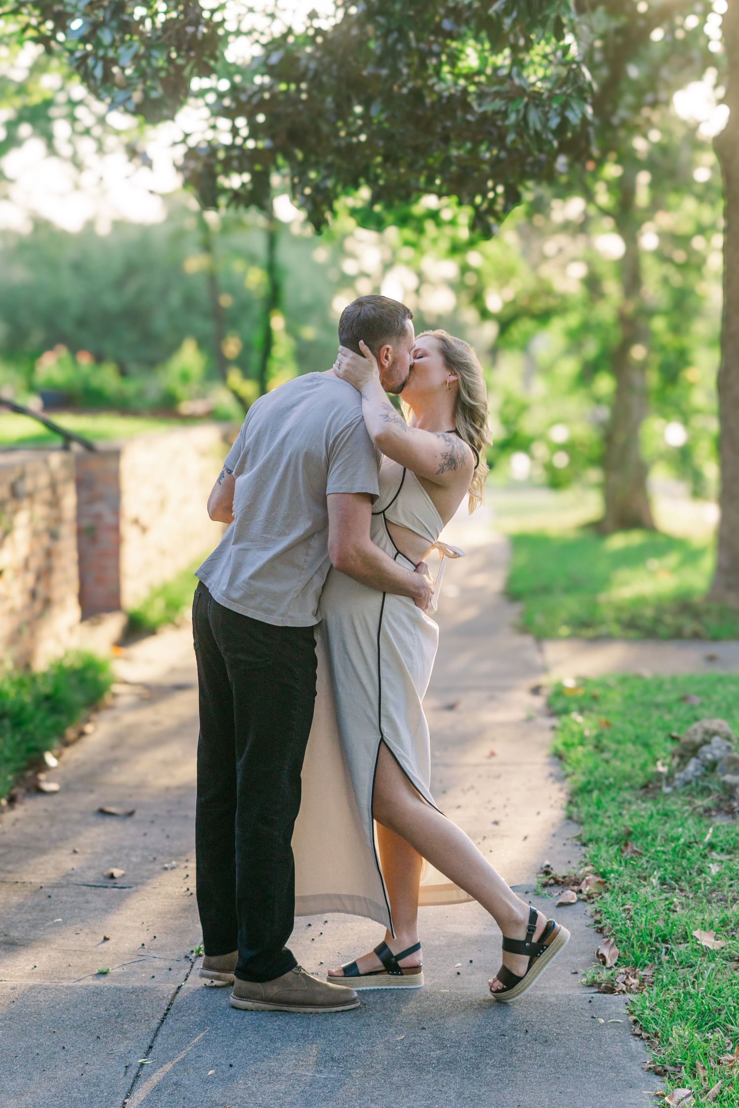 Romantic couple embraces on a tree-lined pathway during golden hour.