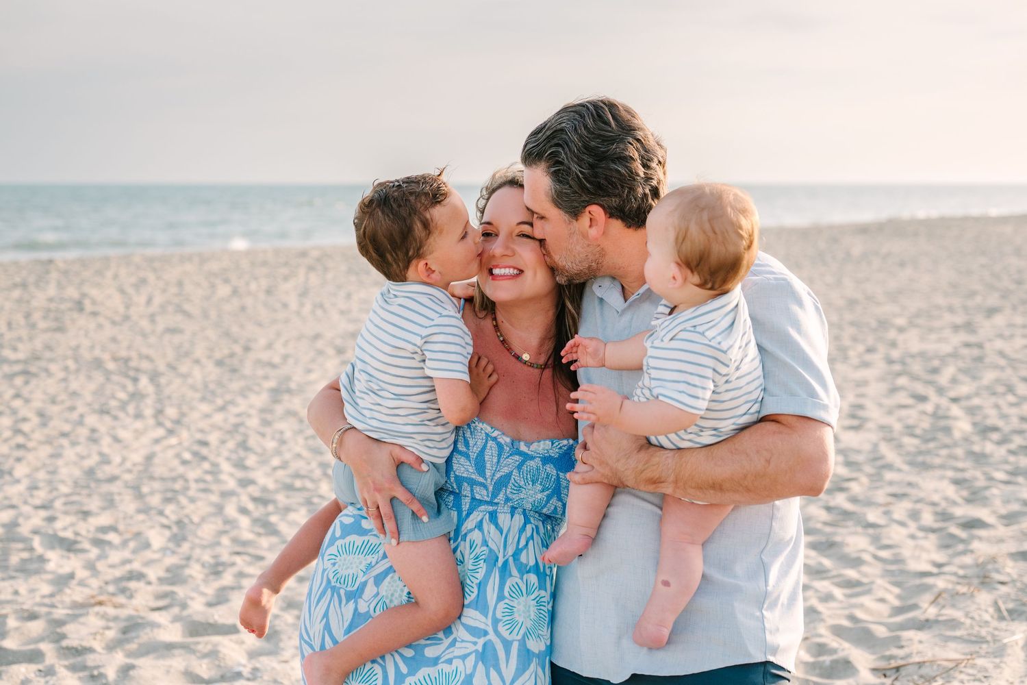 Family sharing joyful moment together on sandy beach during sunset photo session.